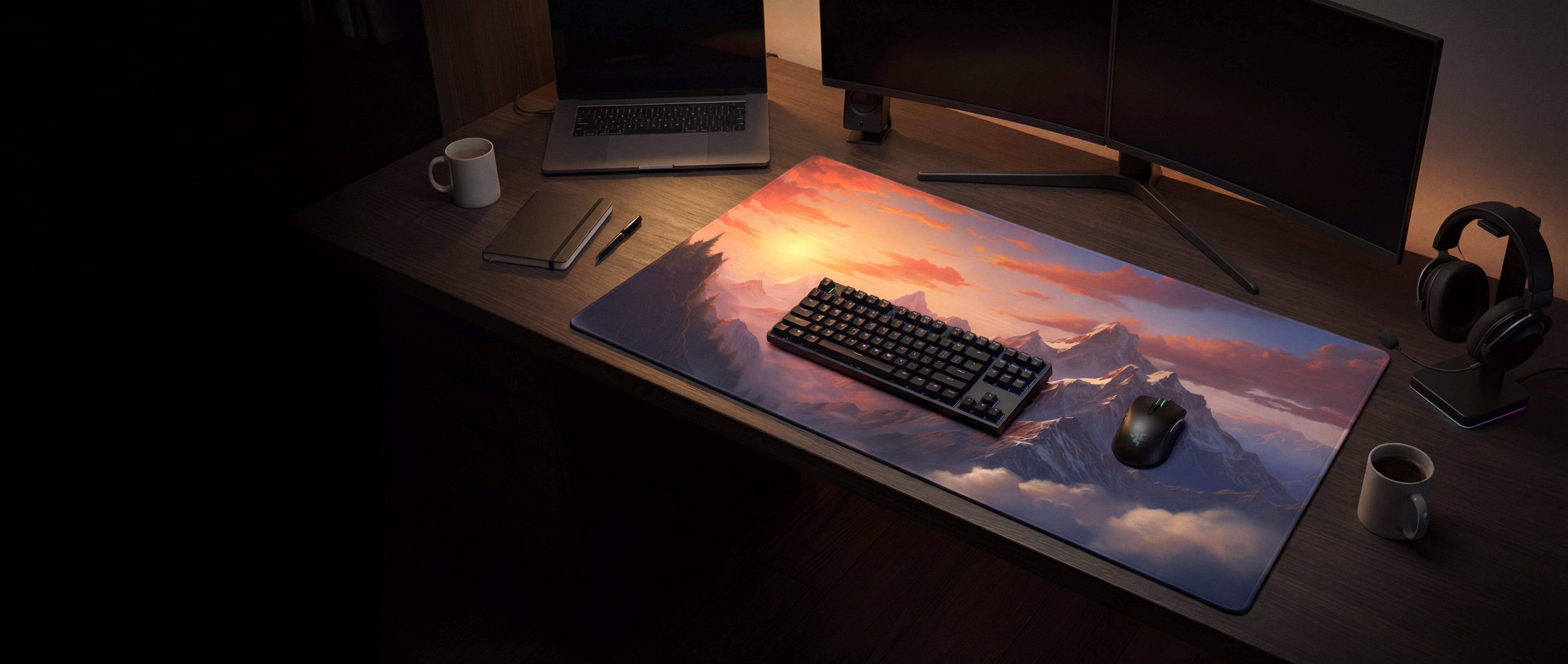 A rectangular gaming mousepad featuring a vibrant sunset over mountain peaks design with soft pink, orange and purple hues.
