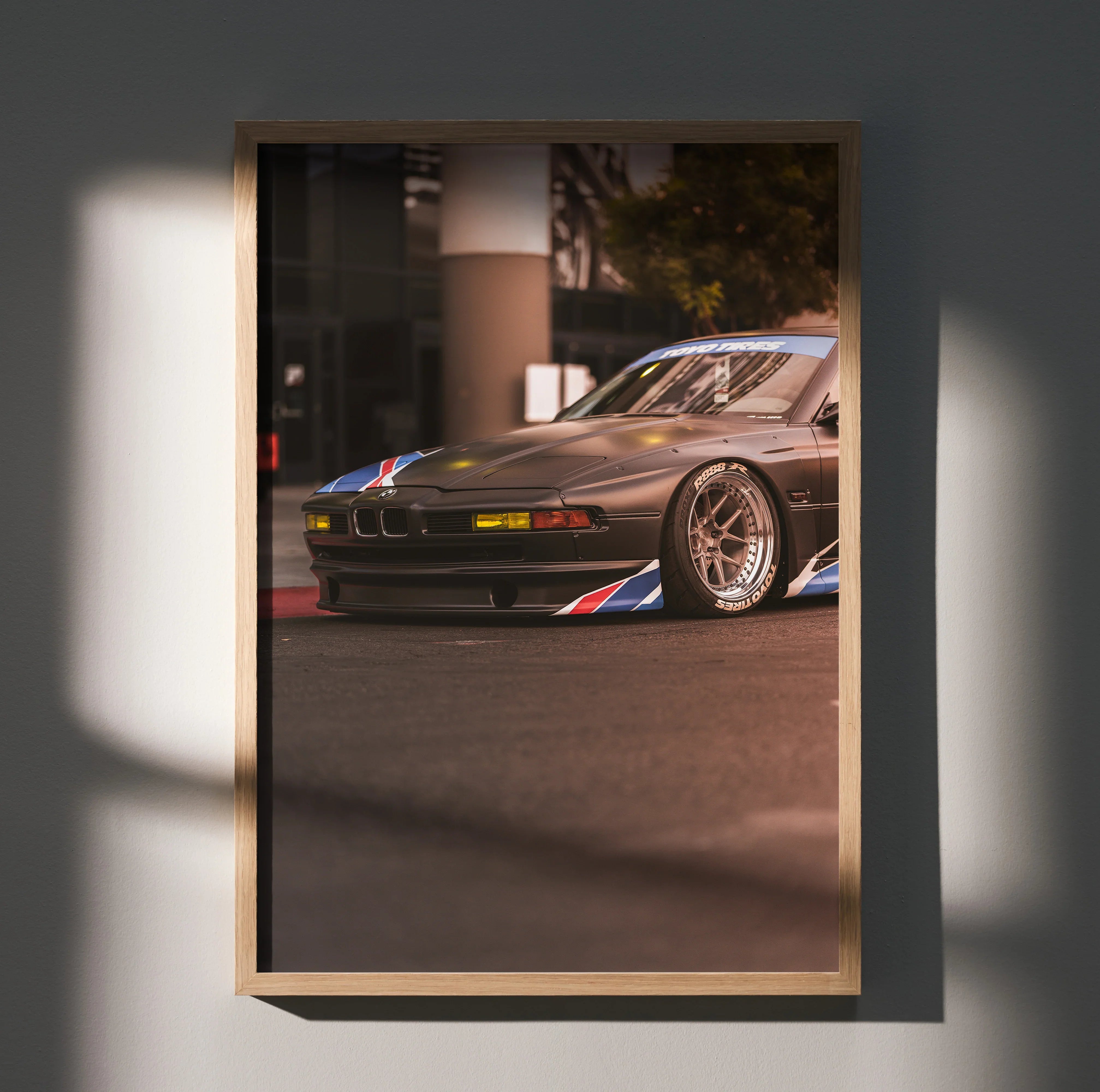 BMW E31 850ci poster featuring silver classic car with blue and red accents, framed wall art.