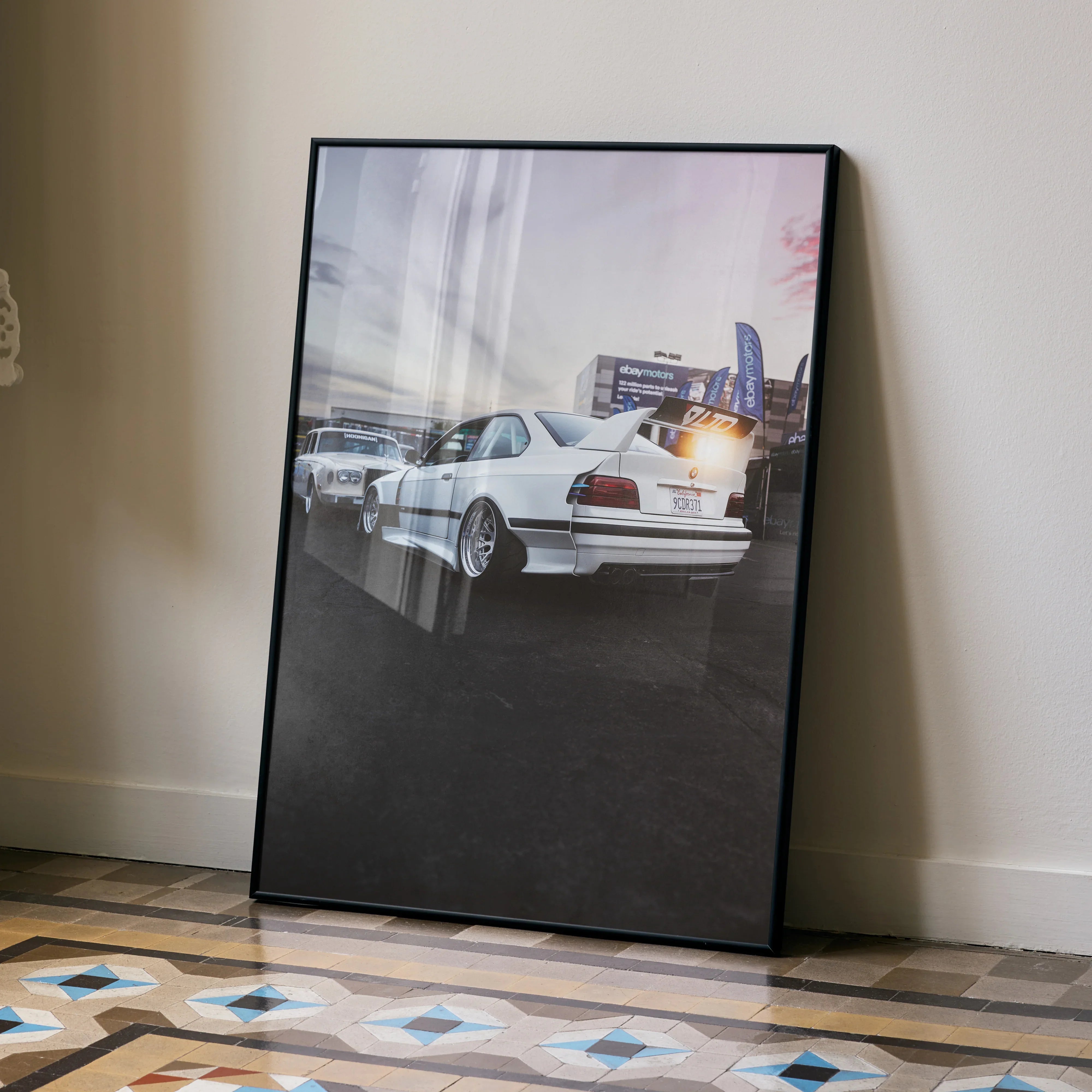 BMW E36 M3 widebody white car poster leaning against wall on patterned floor wall art.