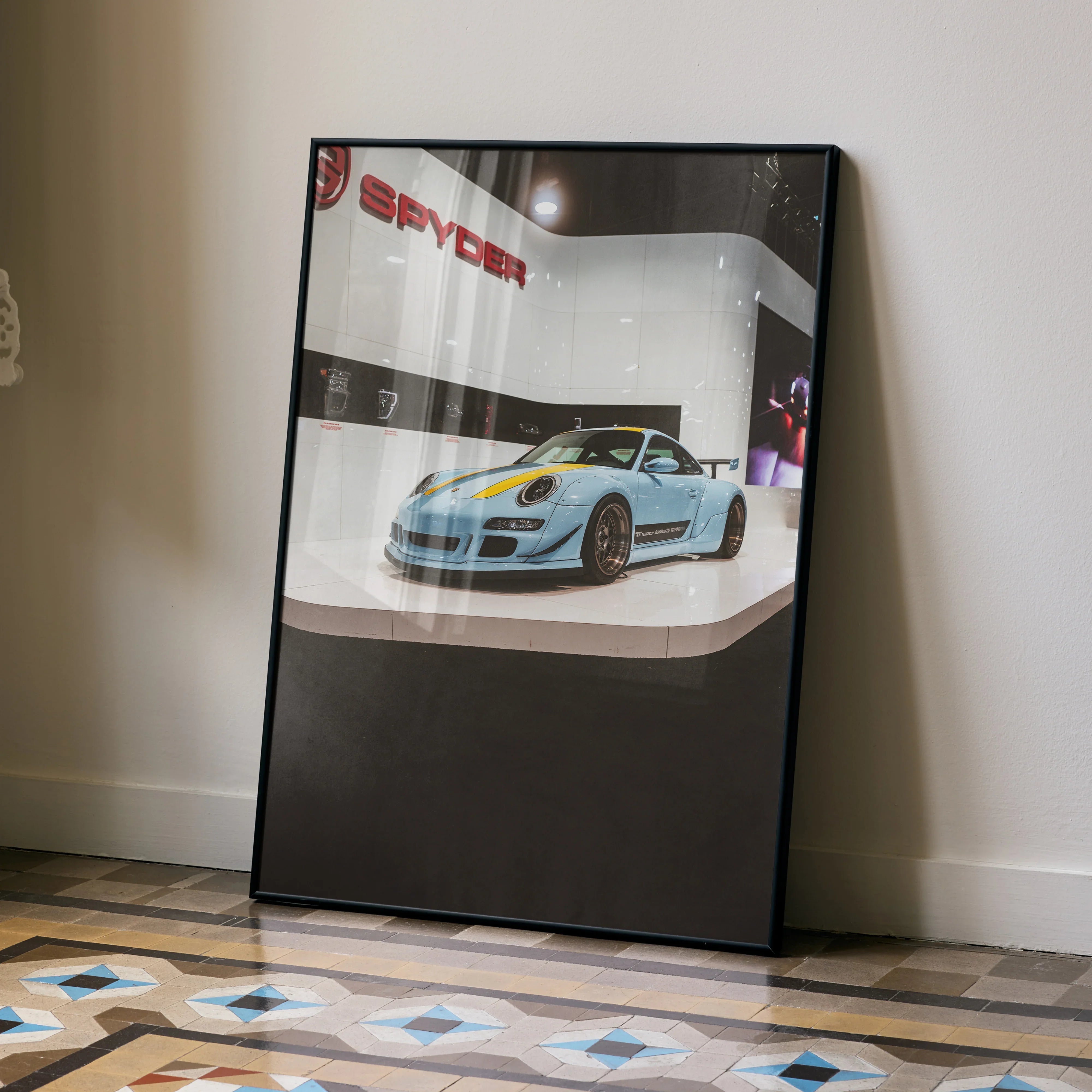 Porsche 911 Carrera 4 in blue sports car wall art poster leaning against a wall on patterned floor.