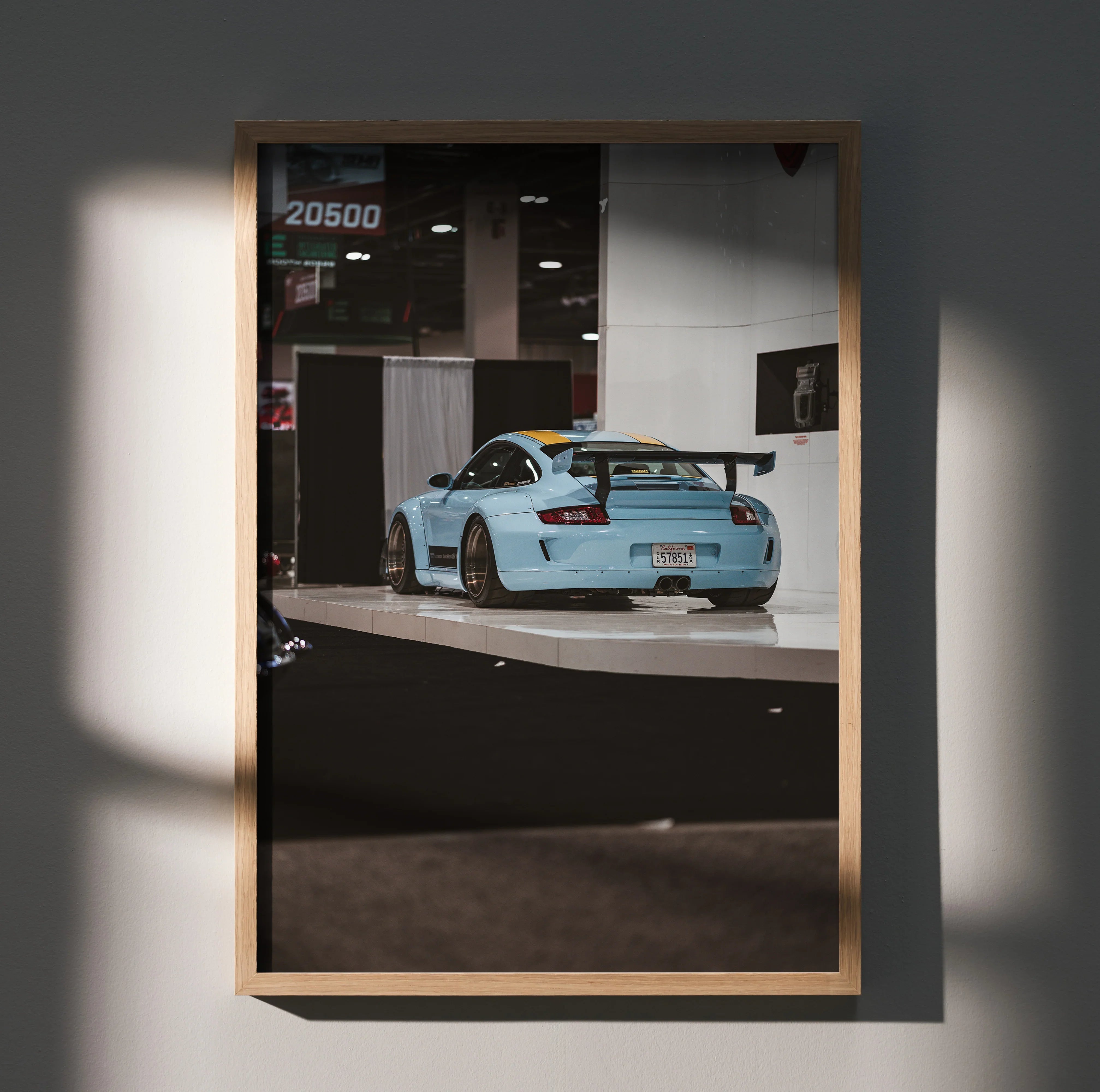 Porsche 911 Carrera 4 in light blue displayed on wall art poster with wooden frame.