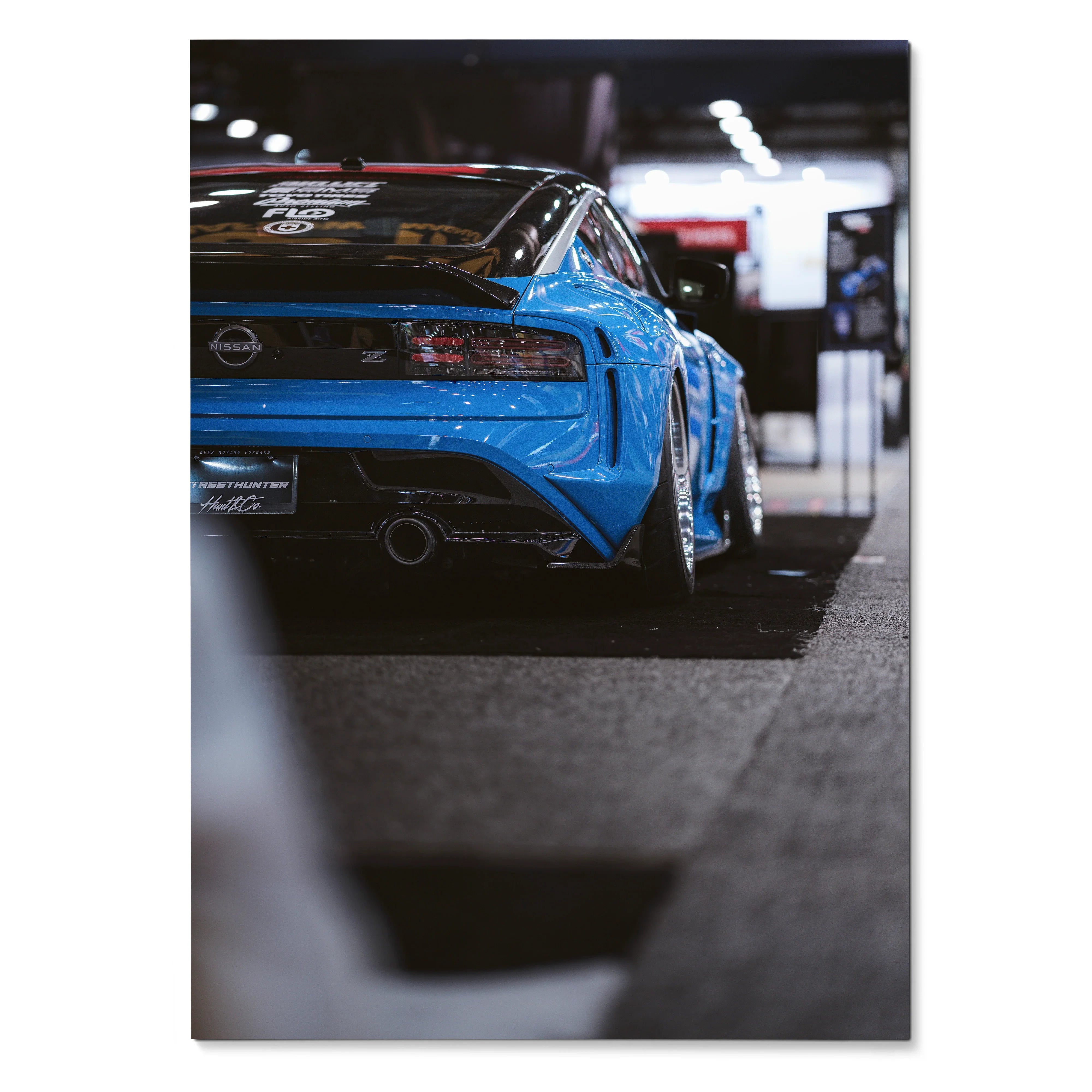 Blue Nissan Z (RZ34) rear view with wide body kit poster, sleek automotive wall art in garage setting.