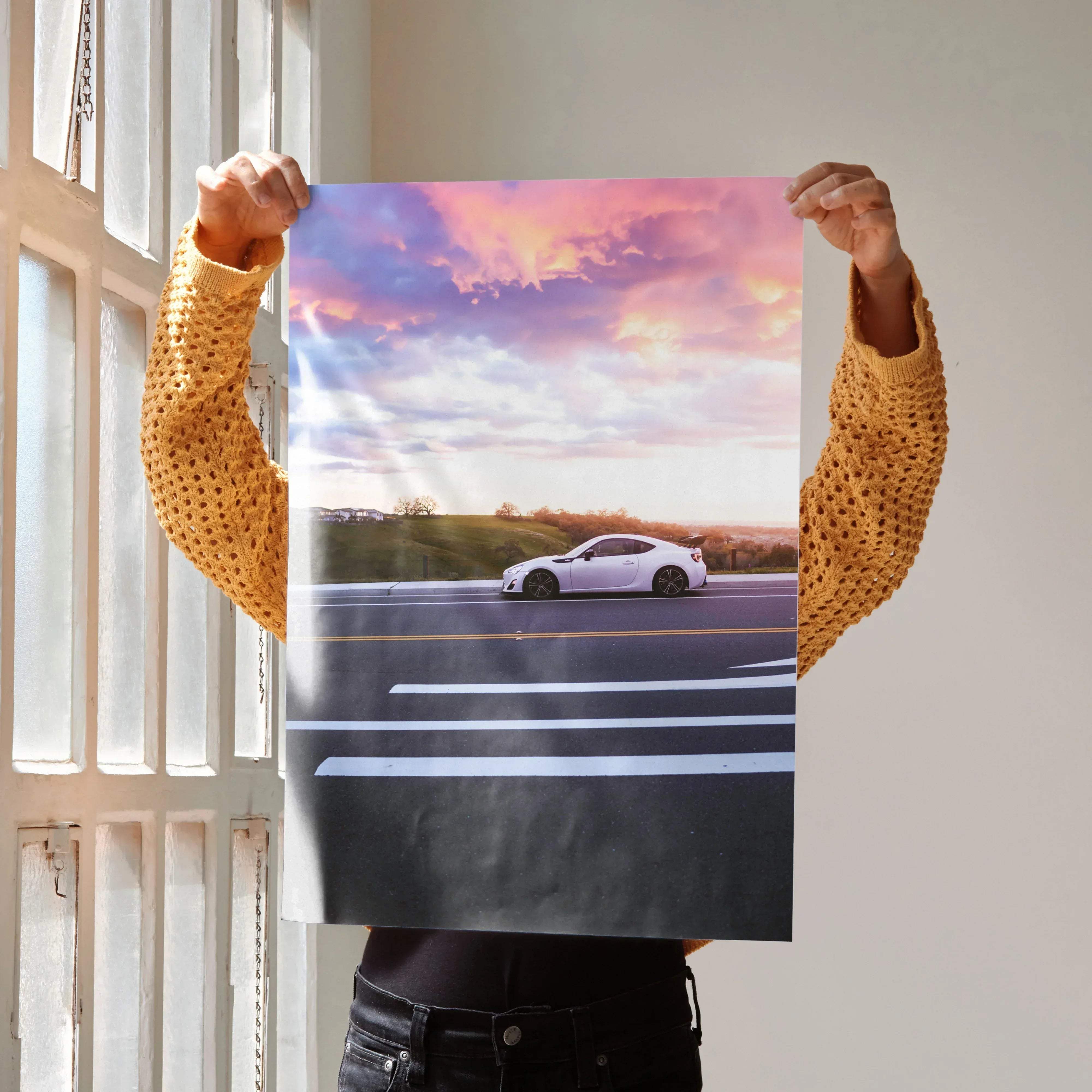 A white sports car with black rims on a printed toyota frs high resolution car poster against a sunset sky