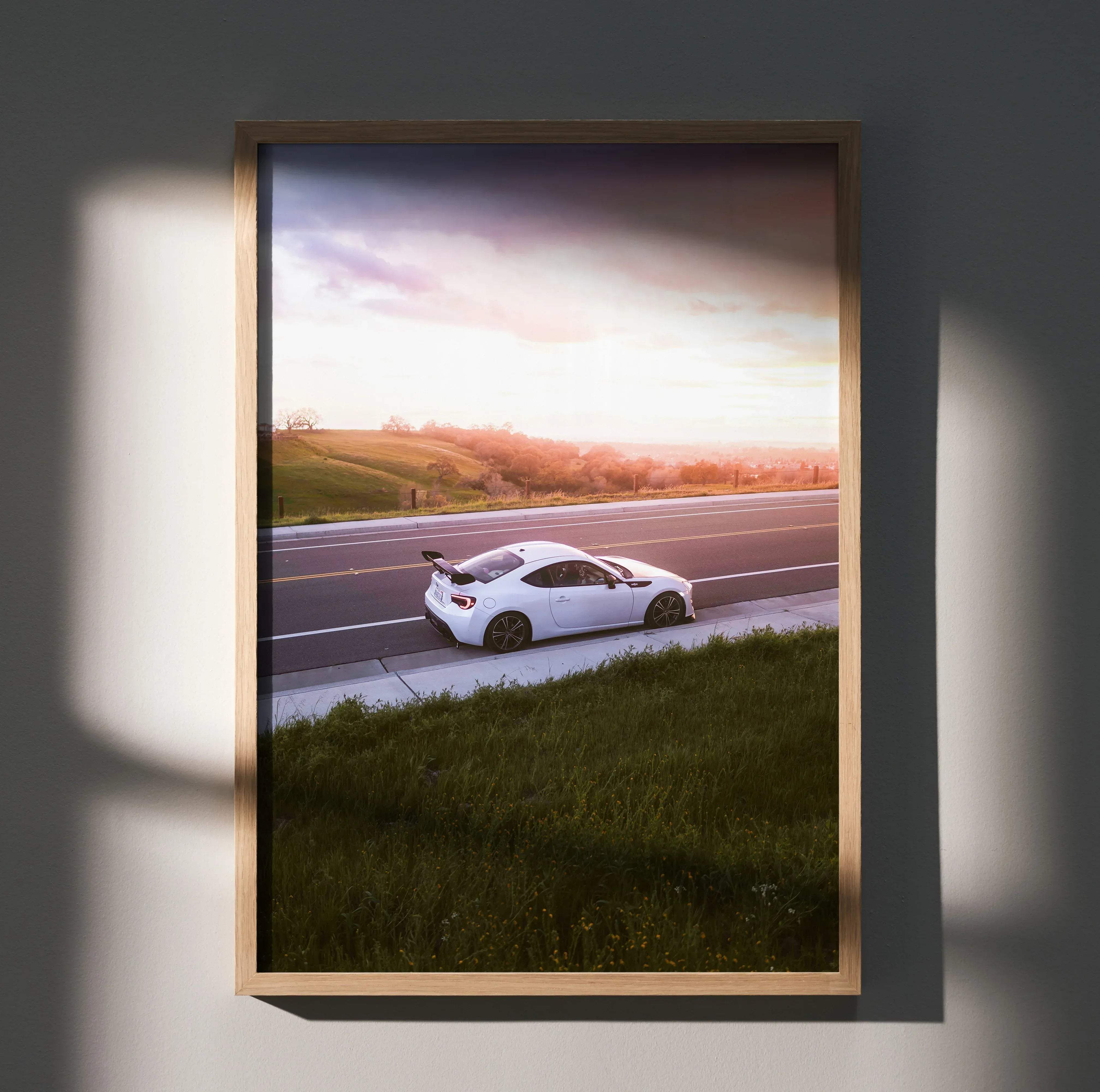 A framed Toyota FRS high resolution car poster showing a white sports car at sunset in a light wood frame