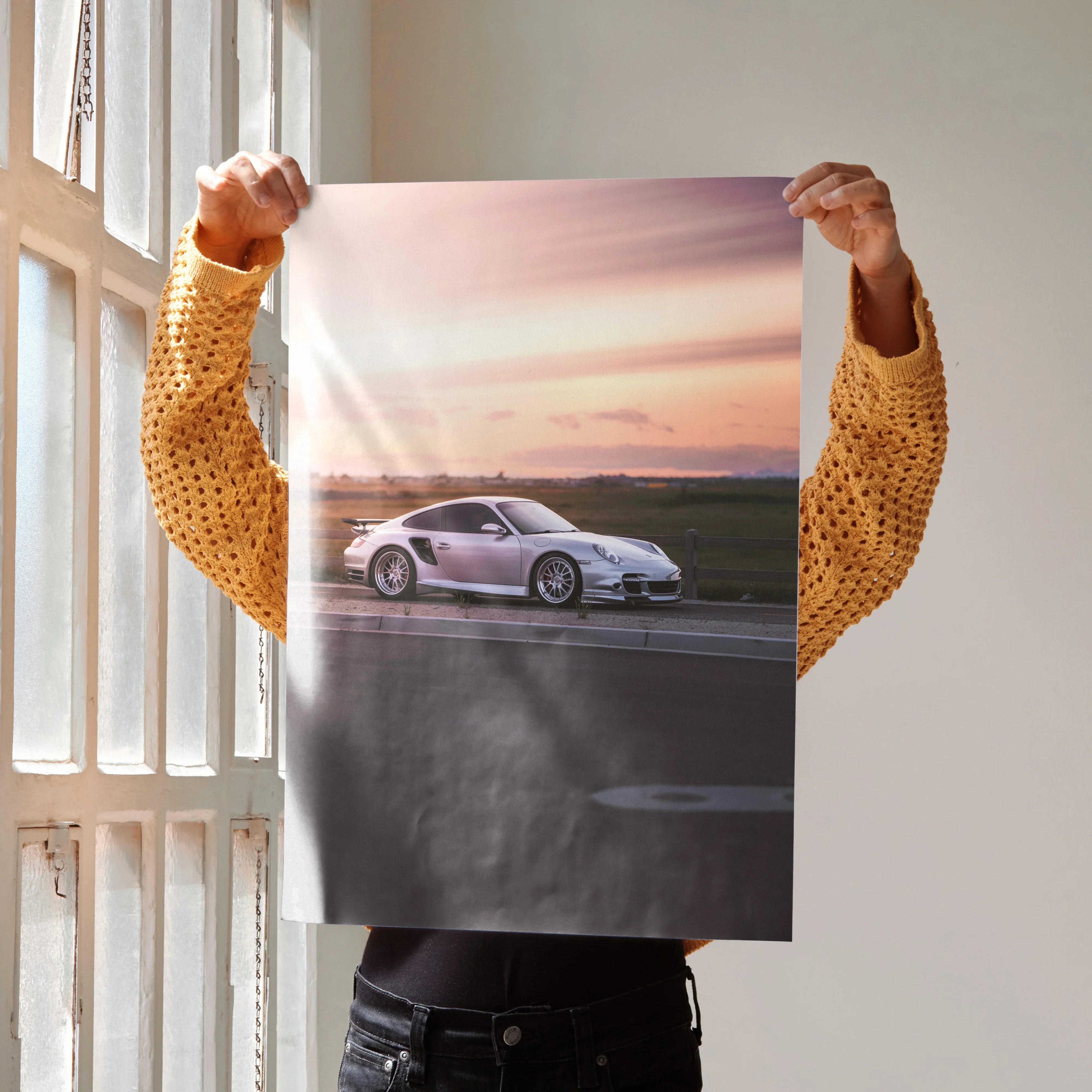 Porsche 911 Turbo at sunset on poster held against neutral background, wall art with vivid colors.