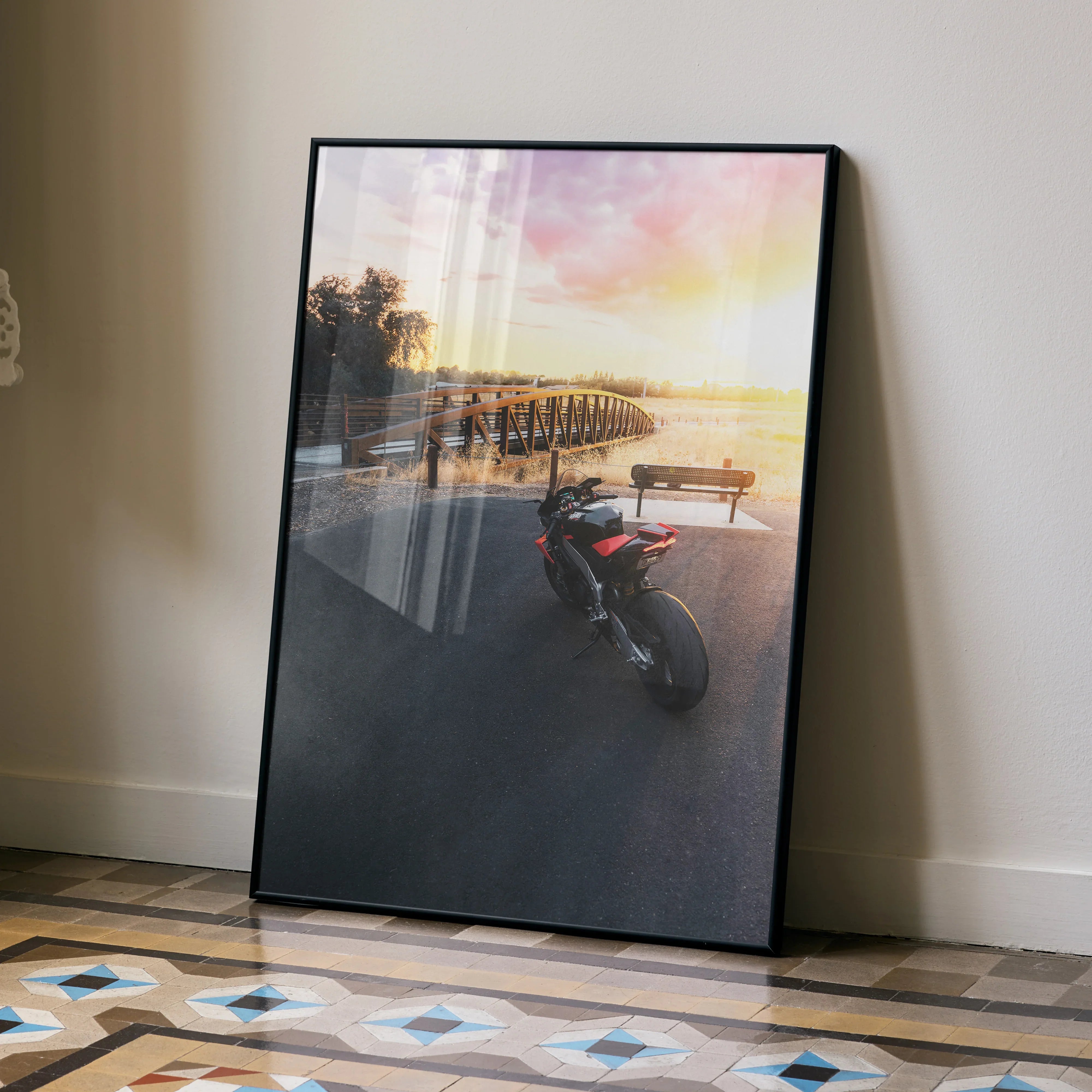 Aprilia RSV4 motorcycle parked near pier at sunset Poster wall art in black frame.