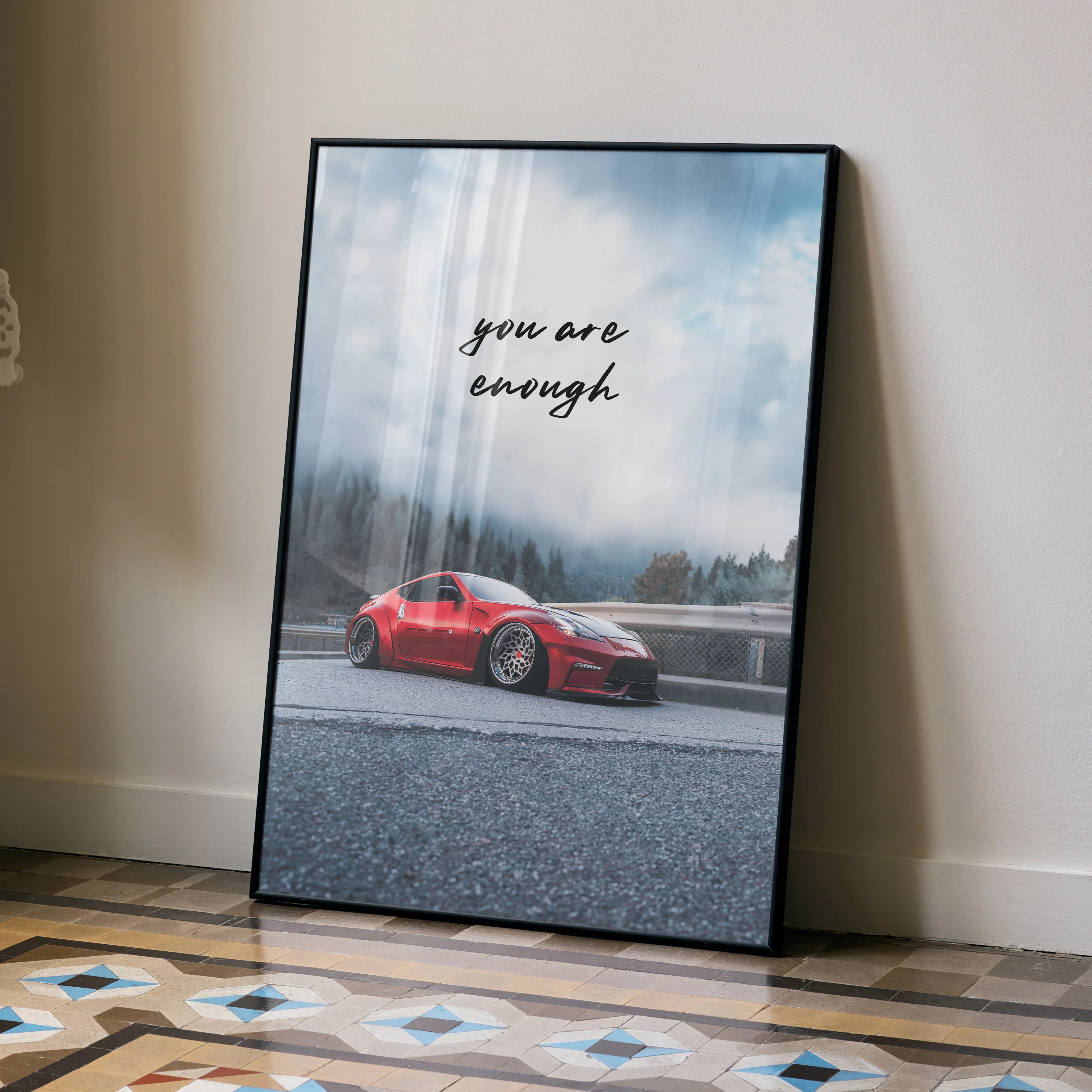 Motivational poster wall art featuring red Nissan 370z with "You are enough" text against cloudy sky.