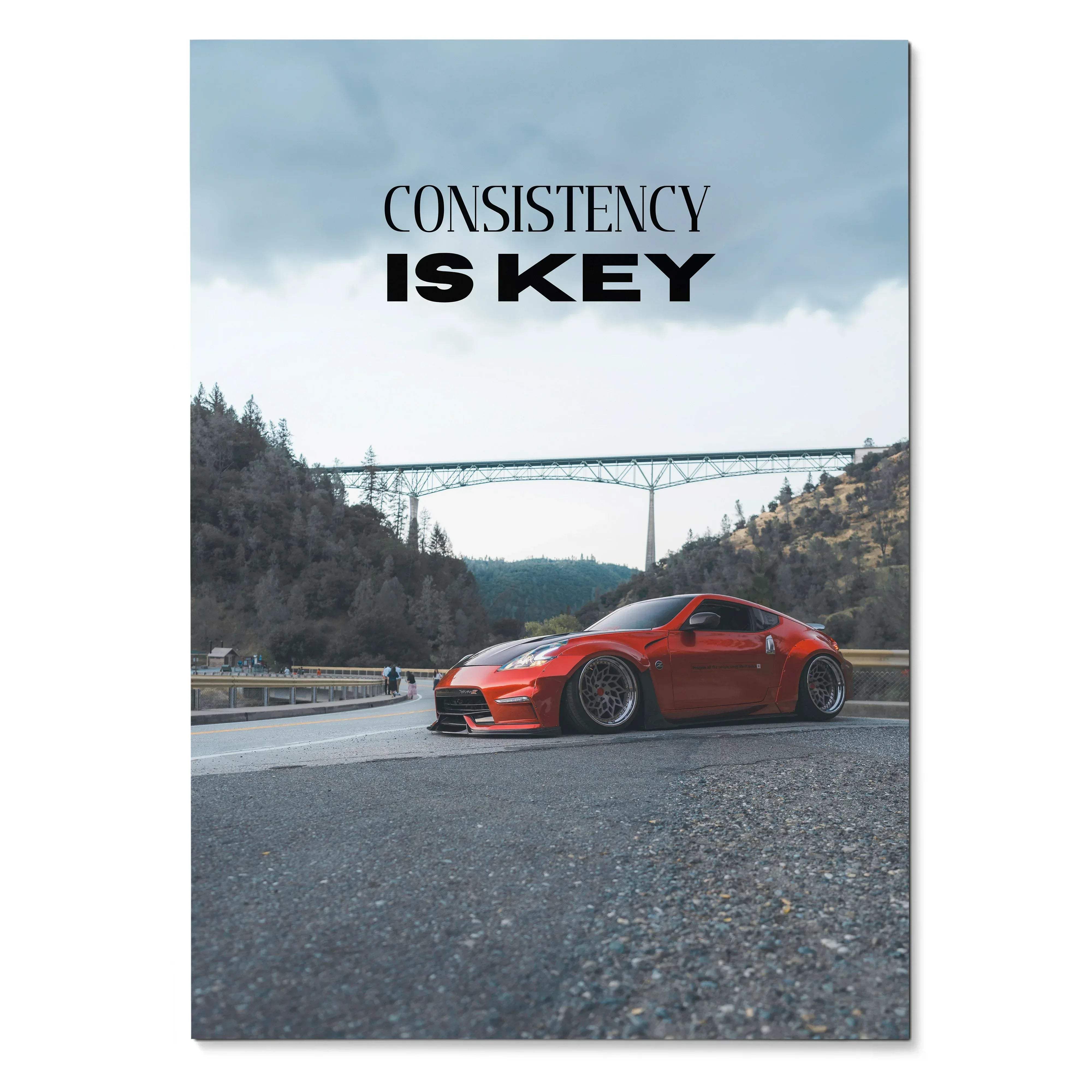 Vibrant red Nissan 370z sports car with custom lowered suspension and dark alloy wheels on a bridge road under overpass