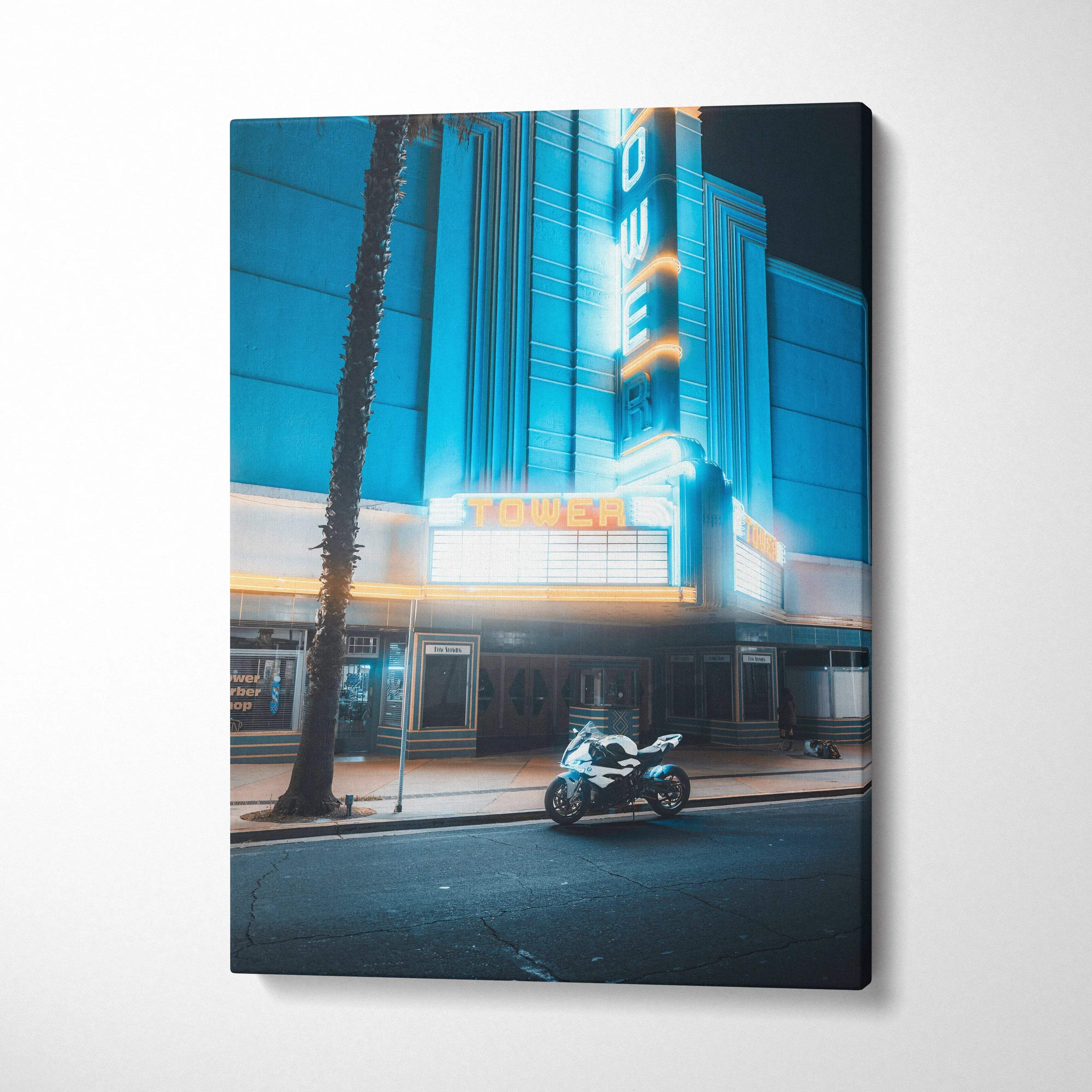 Vertical canvas wall art featuring a BMW S1000RR motorcycle parked in front of a neon-lit theater at night.