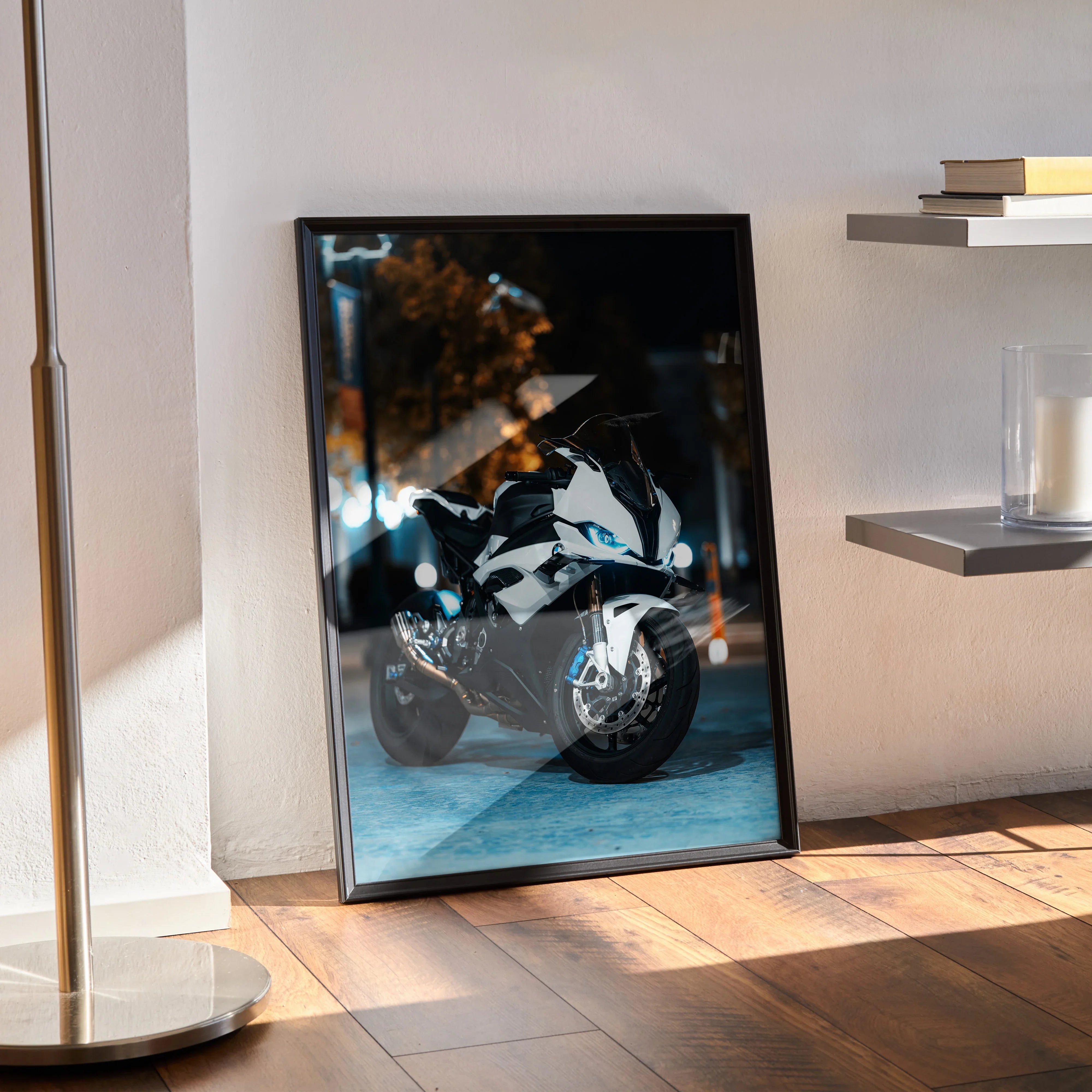 BMW S1000RR motorcycle wall art poster in black frame leaning against wall with sunlight and shadows.