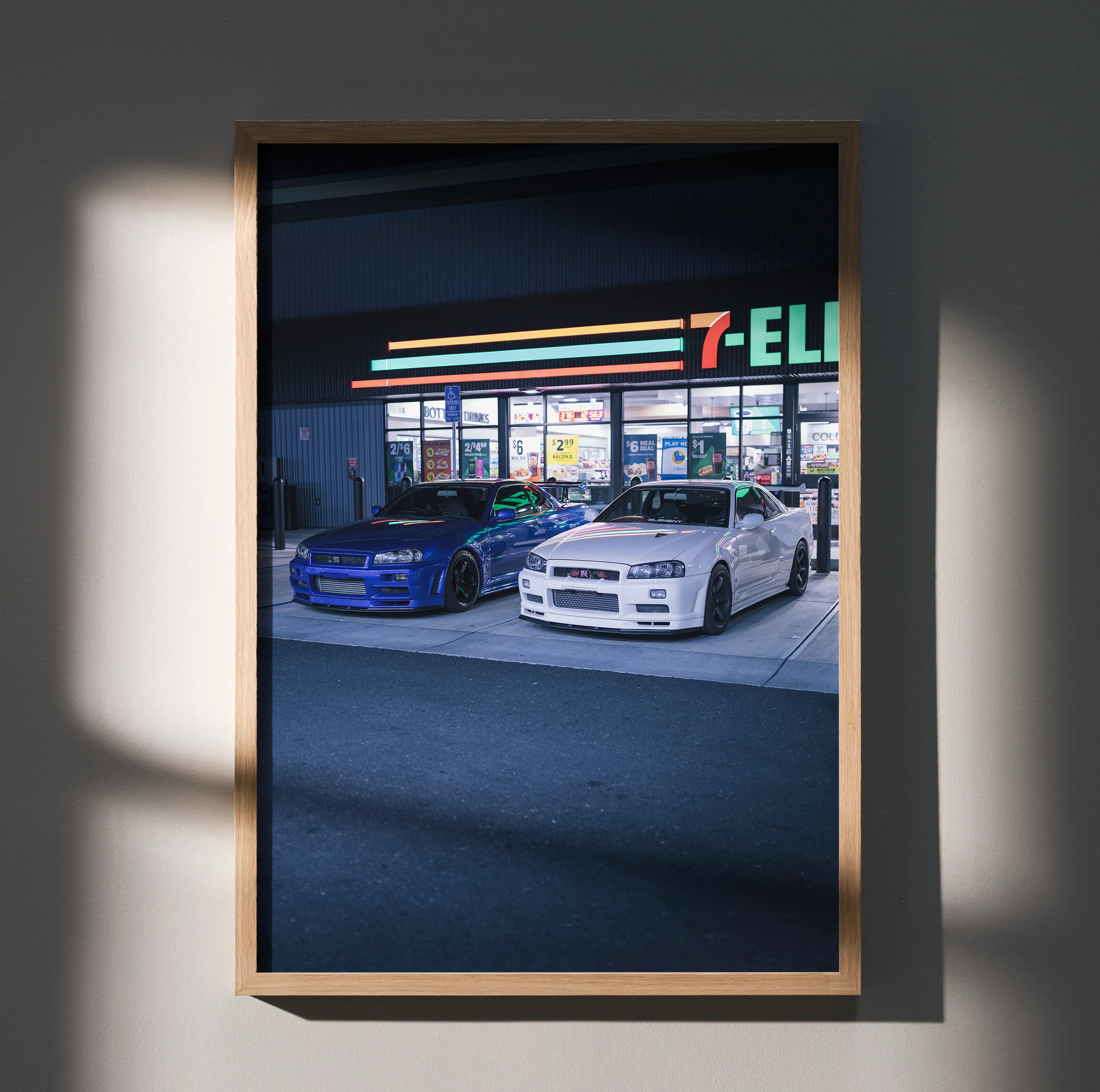 Nissan R34 GTR cars in front of 7-Eleven at night poster wall art in wooden frame.