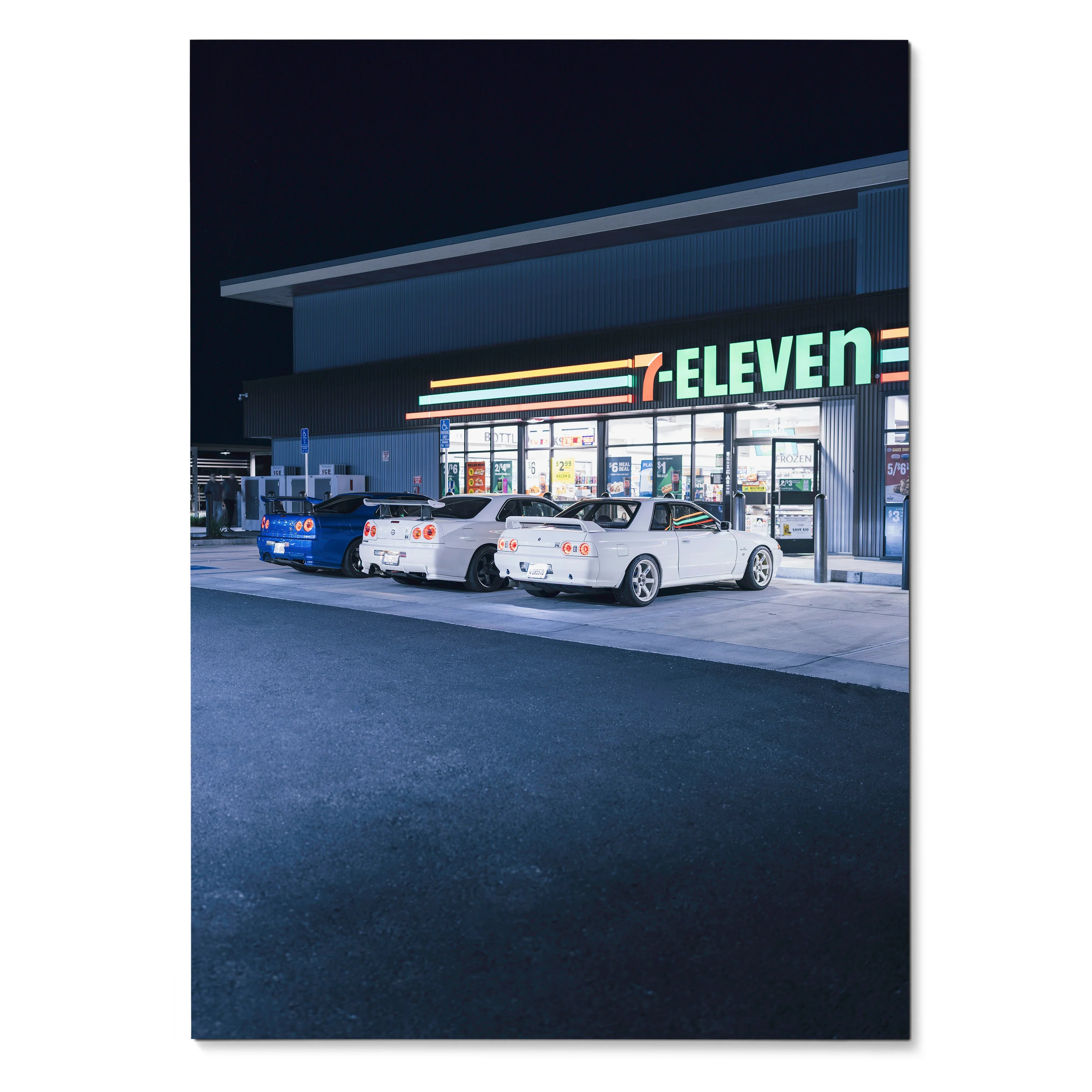 Poster wall art featuring white Nissan R32 and R34 GTR cars parked outside a 7-Eleven at night.