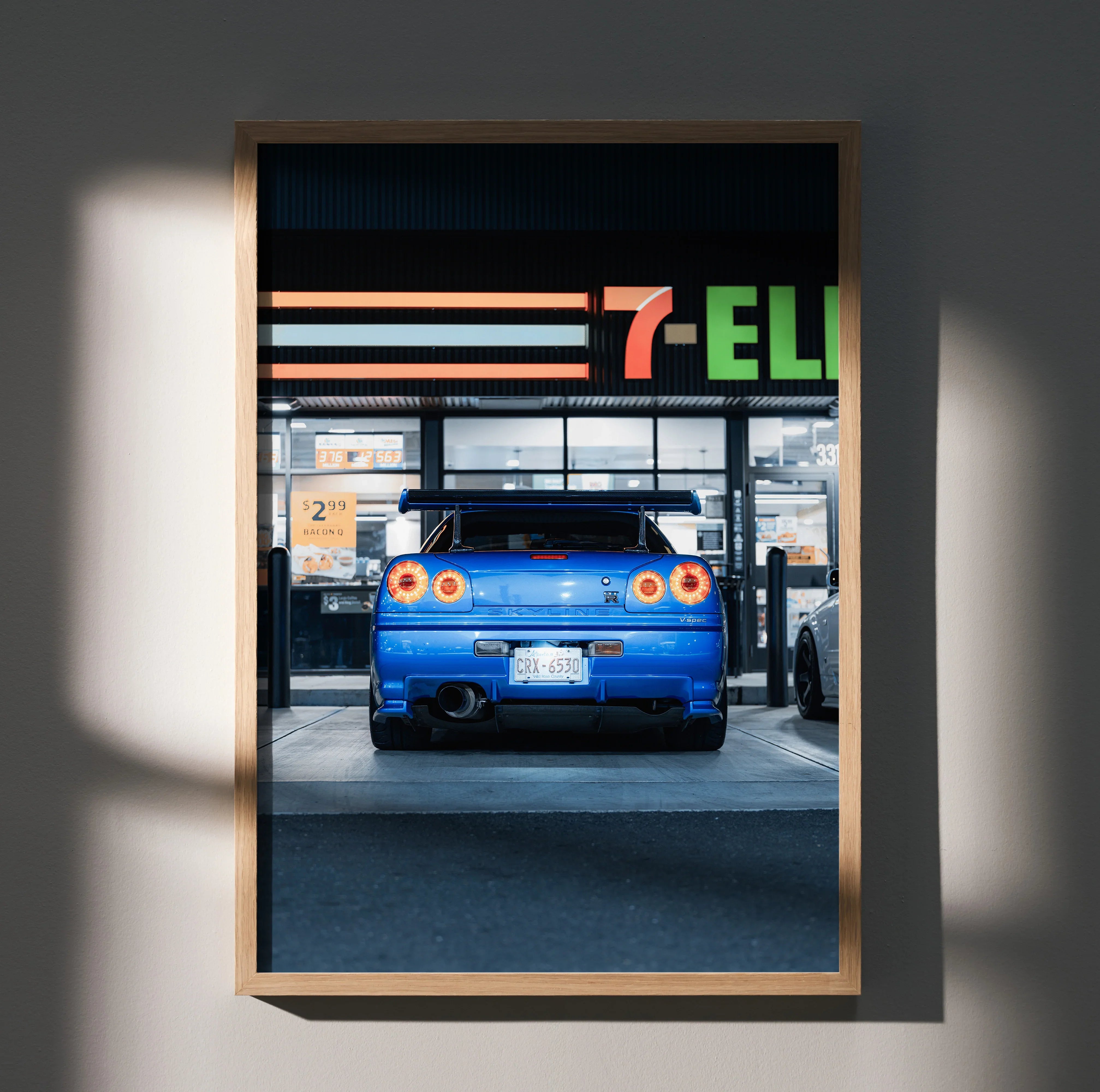 Blue Nissan GTR R34 Skyline poster wall art with rear view at gas station in wooden frame.