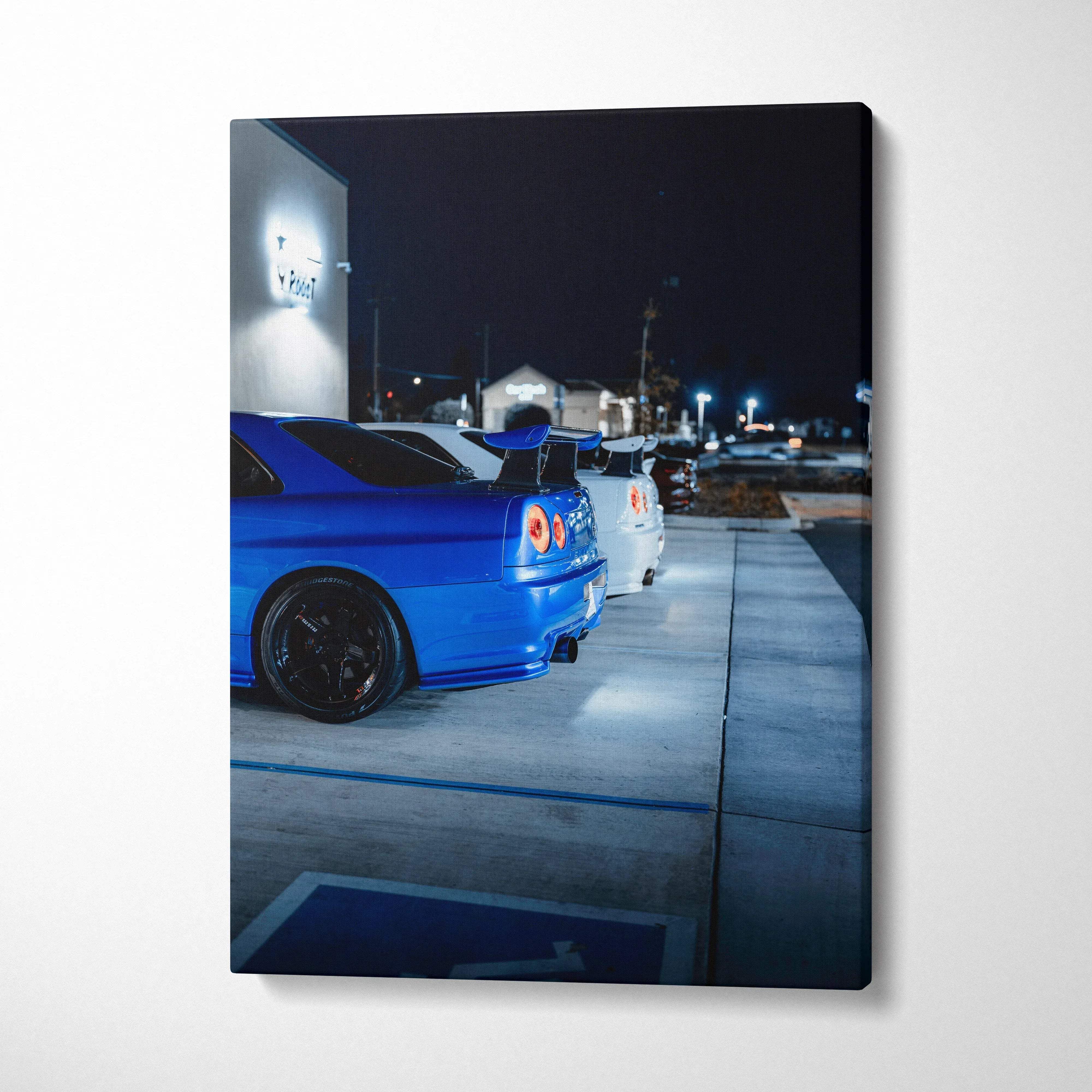 Blue and white Nissan GTR R34 Skyline cars parked at night canvas wall art.