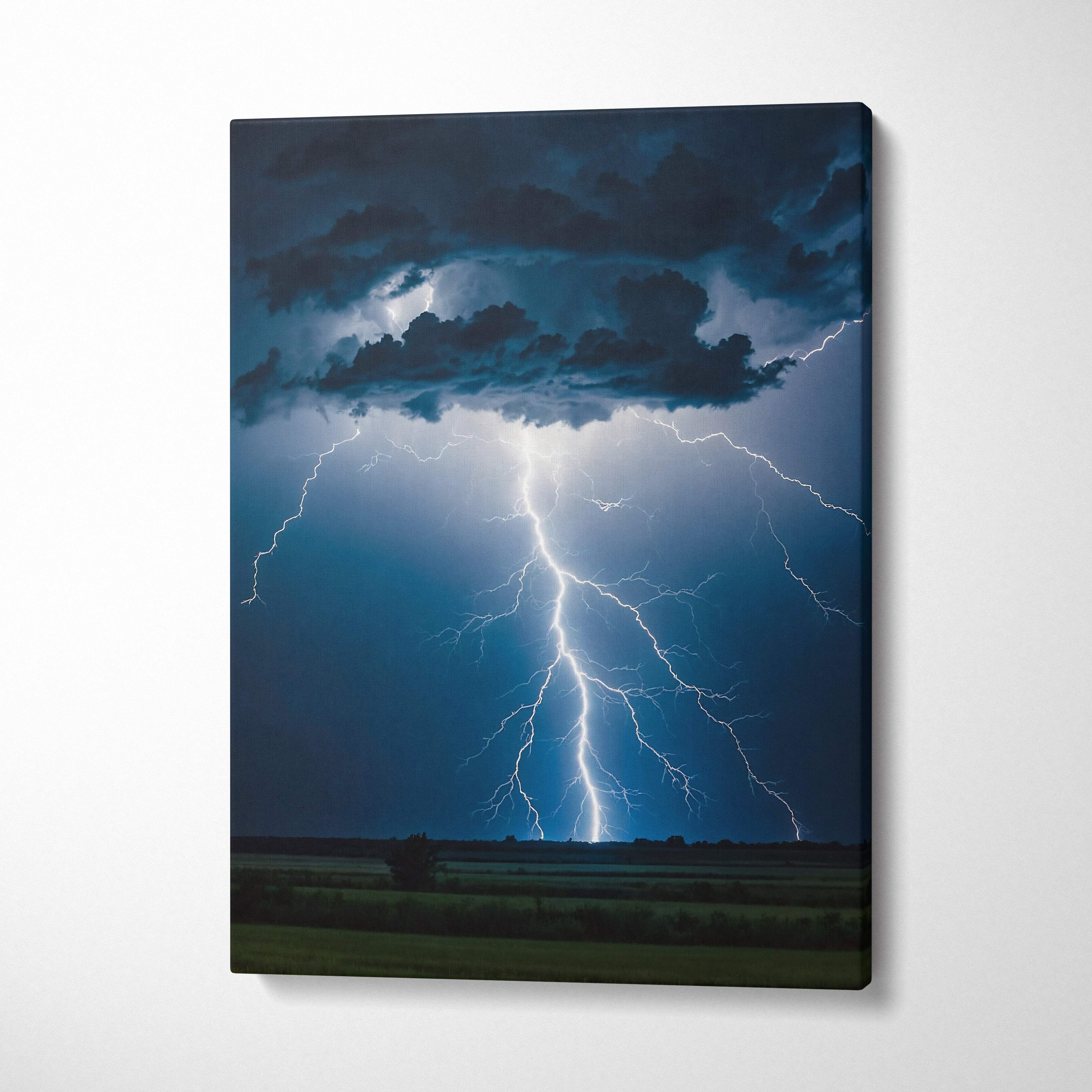 Canvas print of a powerful cloud-to-ground lightning strike with blue and white bolts under dark storm clouds above fields