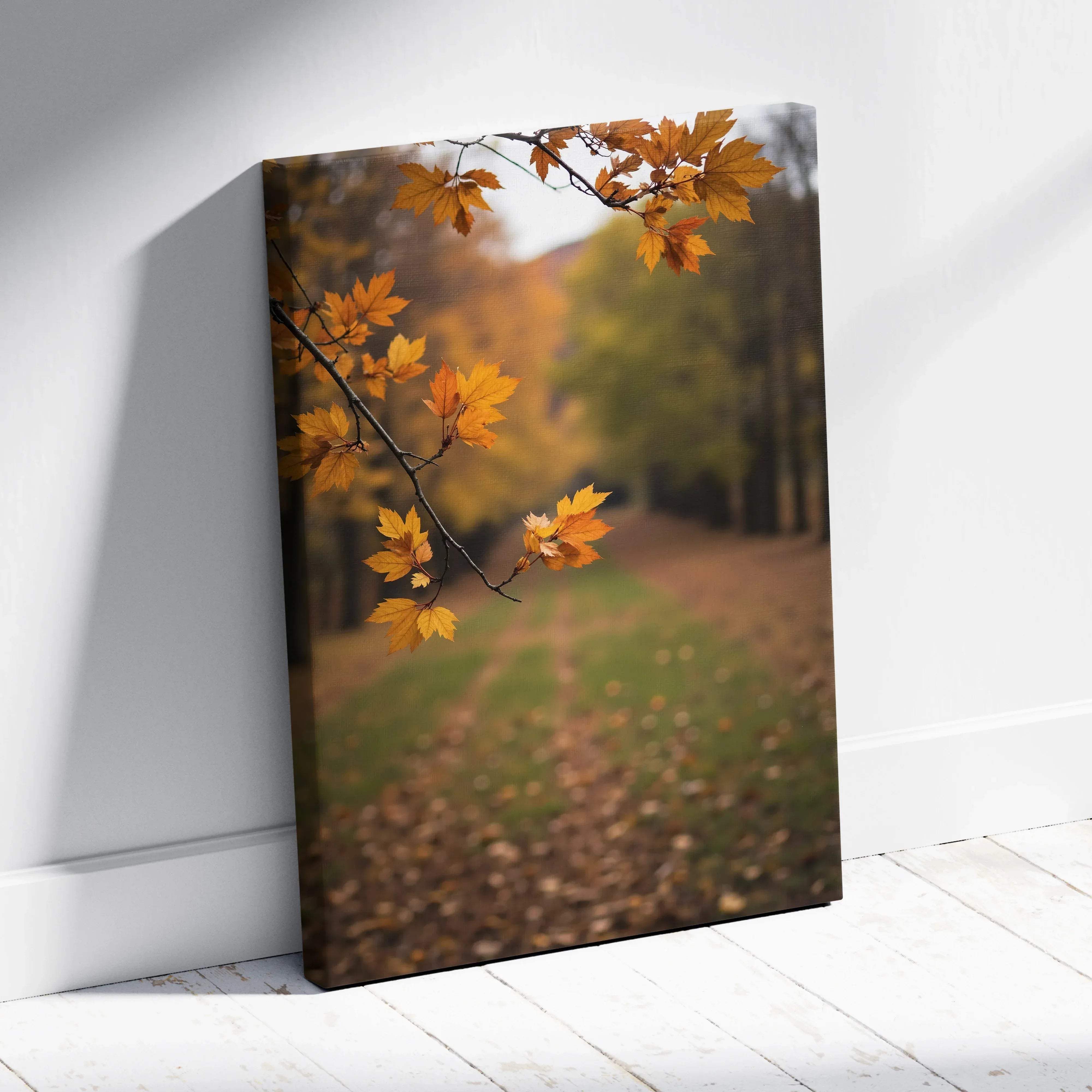A canvas print featuring vibrant orange maple leaves on a branch against a blurred autumn forest path in warm hues