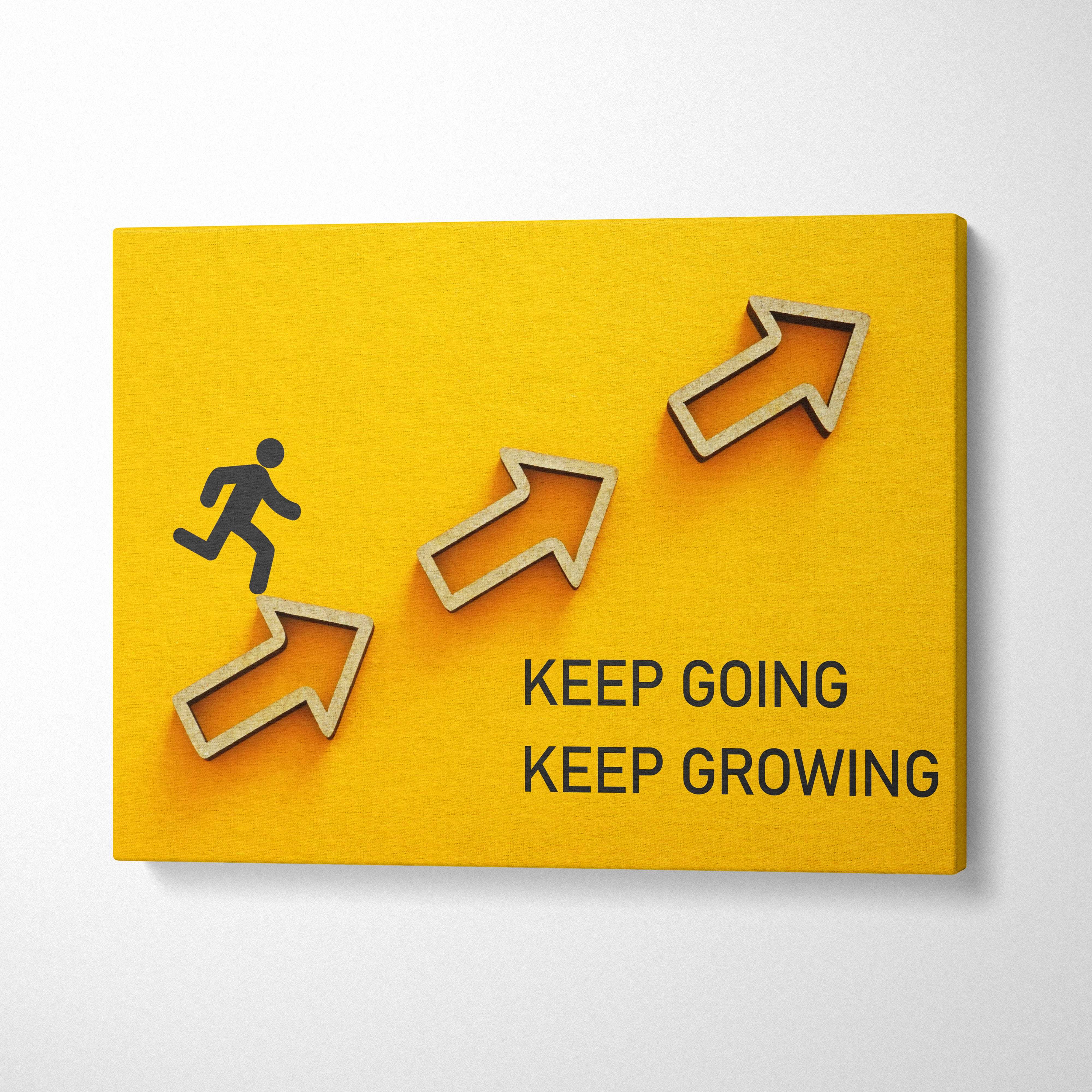 Bright yellow canvas wall art with light wood arrows and a running figure featuring keep going keep growing text