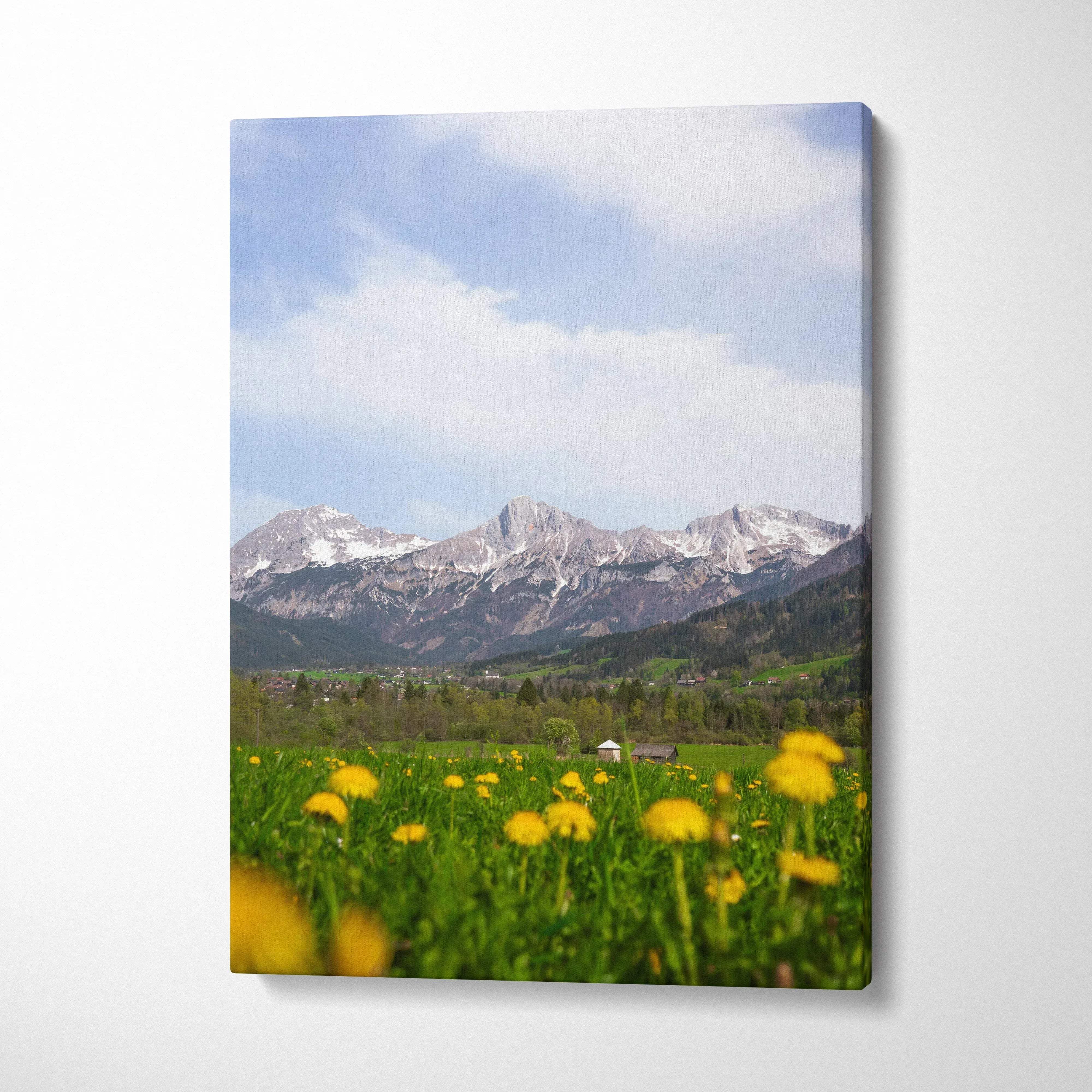 Canvas wall art featuring snow-capped mountains with yellow wildflowers in a green meadow under a blue sky.