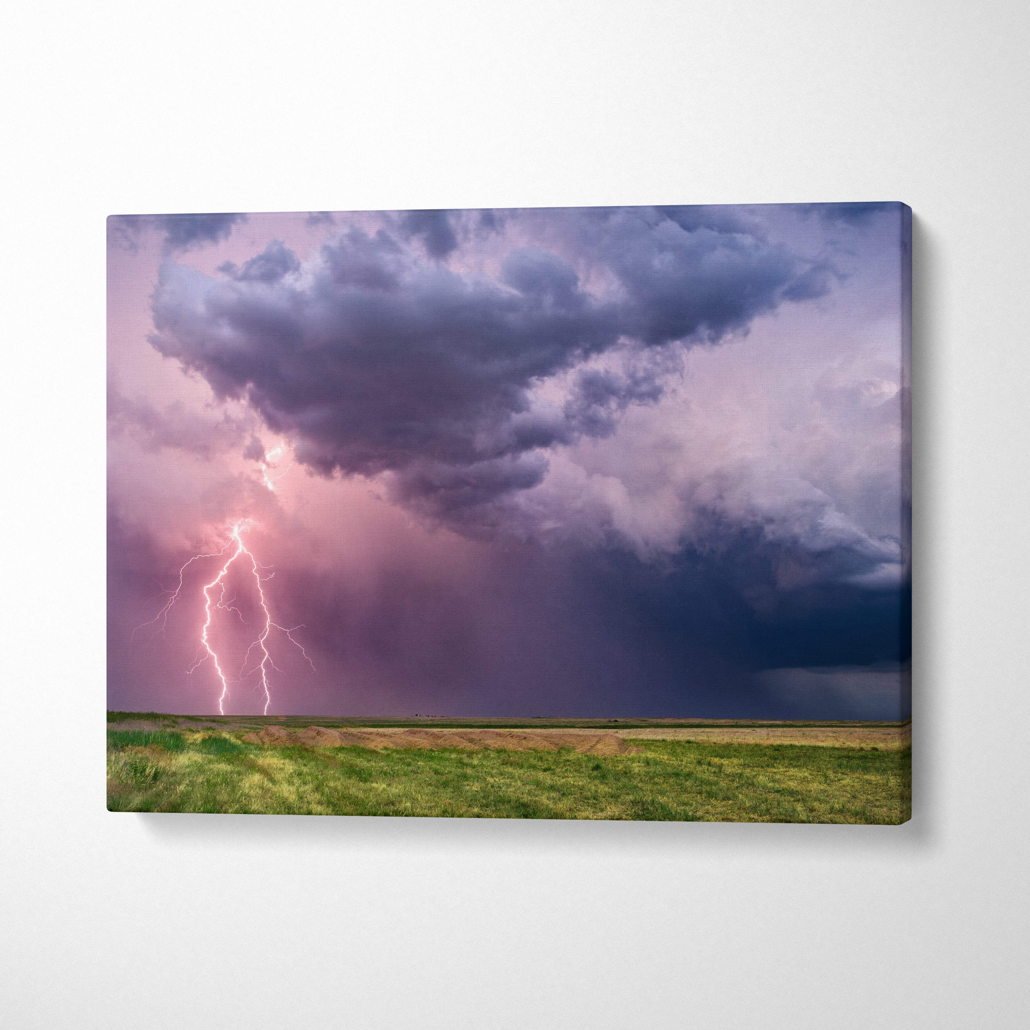 Canvas print of a dramatic lightning storm with purple and pink sky and electric bolt over a green field wall decor