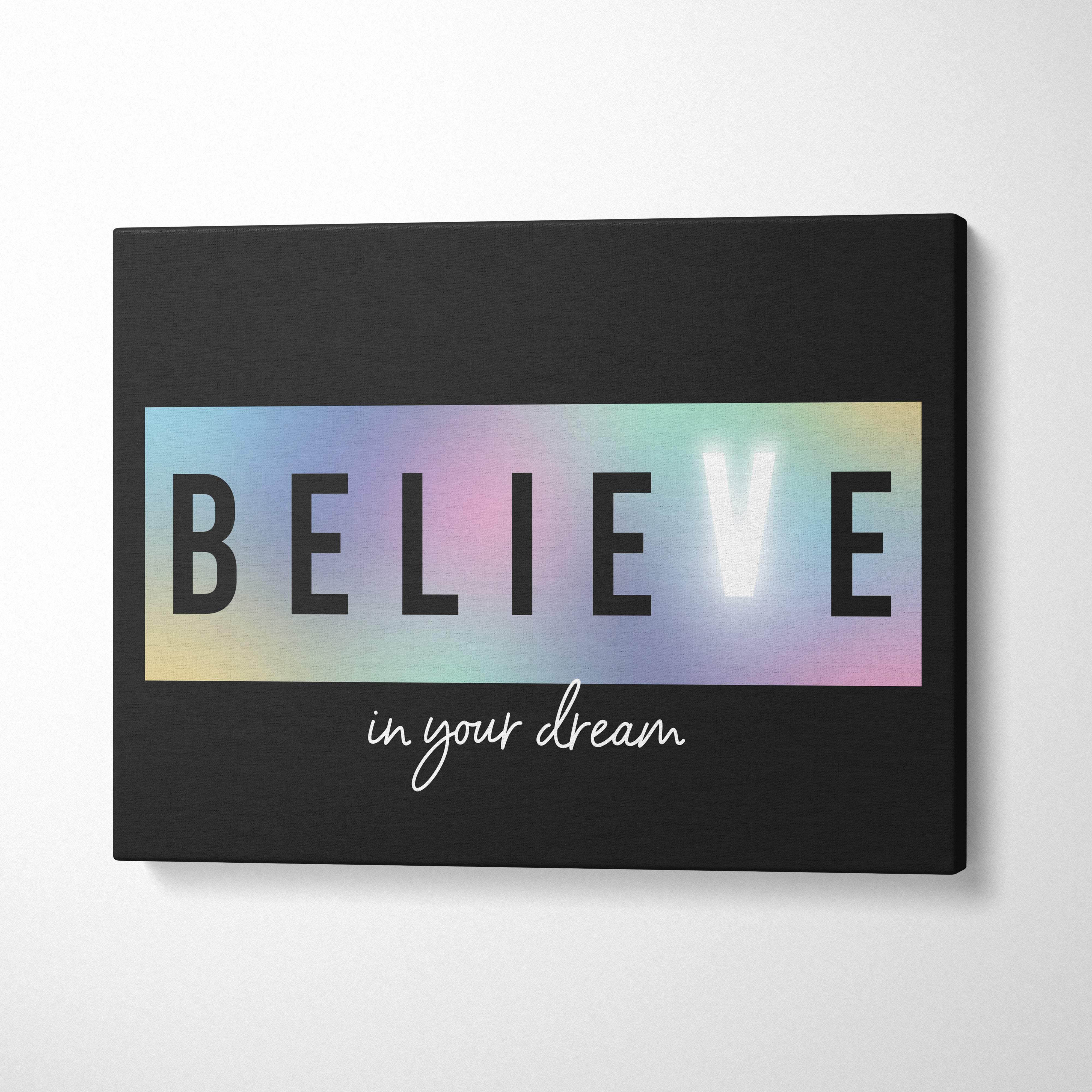 Black canvas print with bold believe in black letters over rainbow rectangle and white cursive in your dream text for inspiration