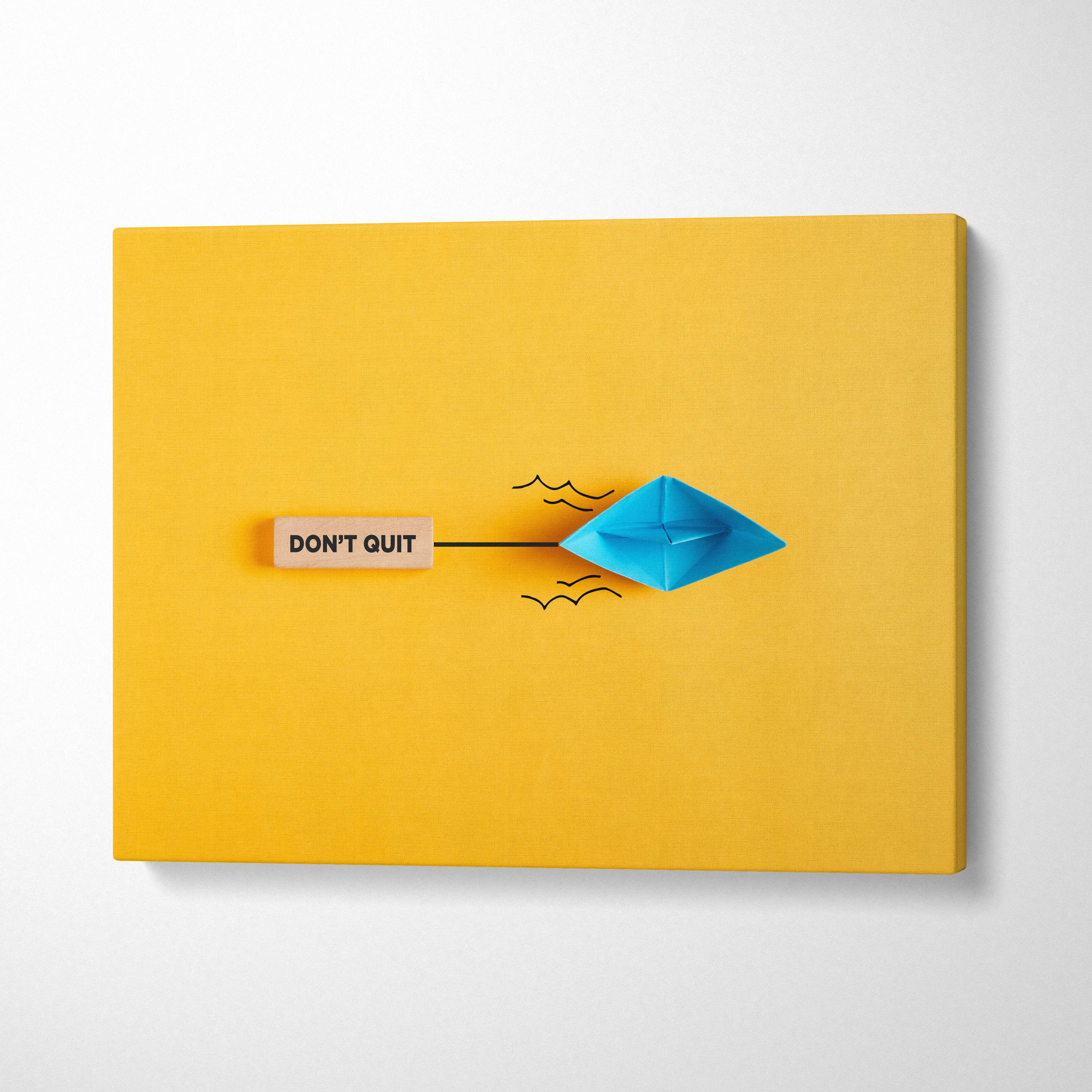 Motivational dont quit canvas wall art with blue origami boat black ink waves on vibrant yellow background and wooden plaque