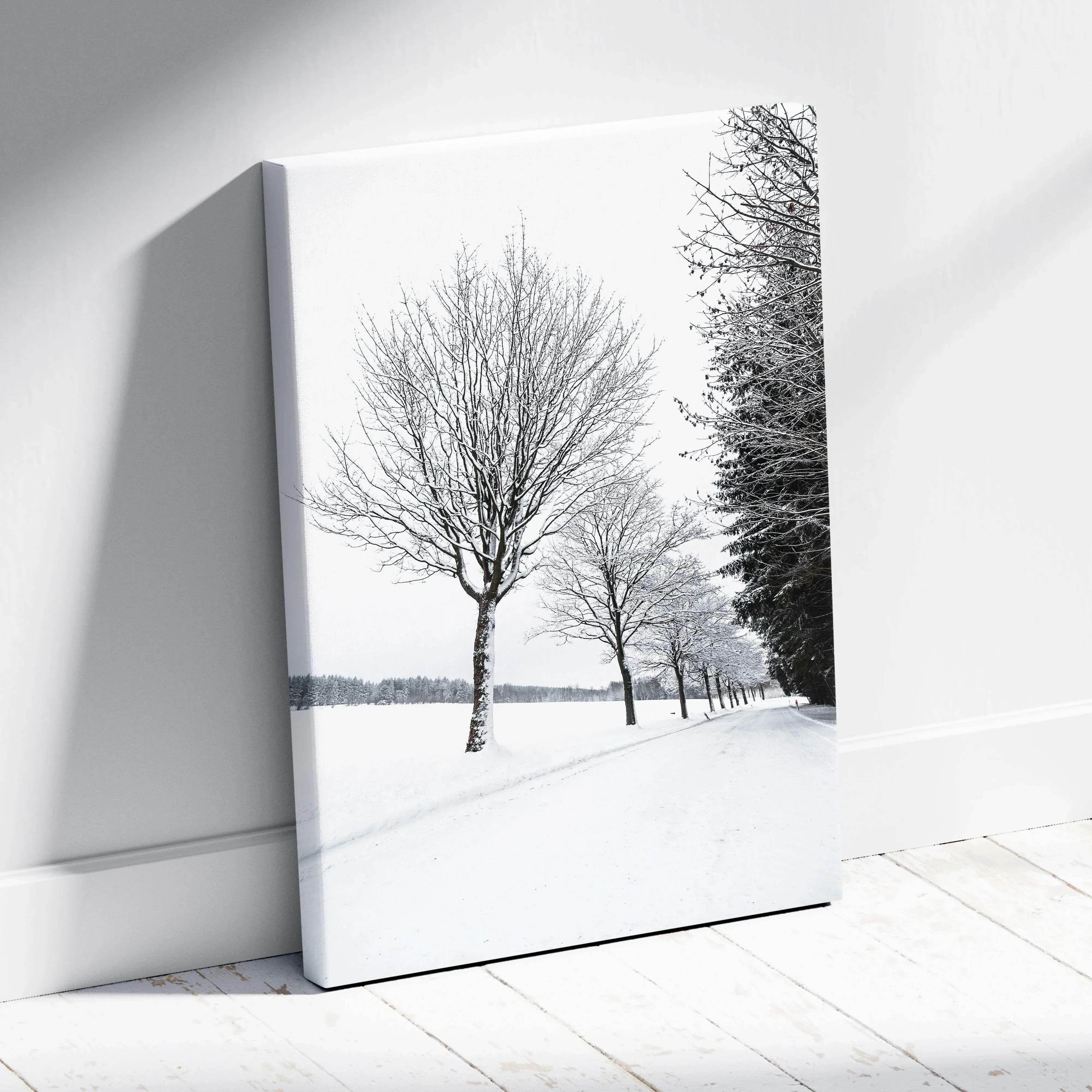 Black-and-white canvas wall art featuring a snow-covered road lined with bare trees in monochrome winter landscape