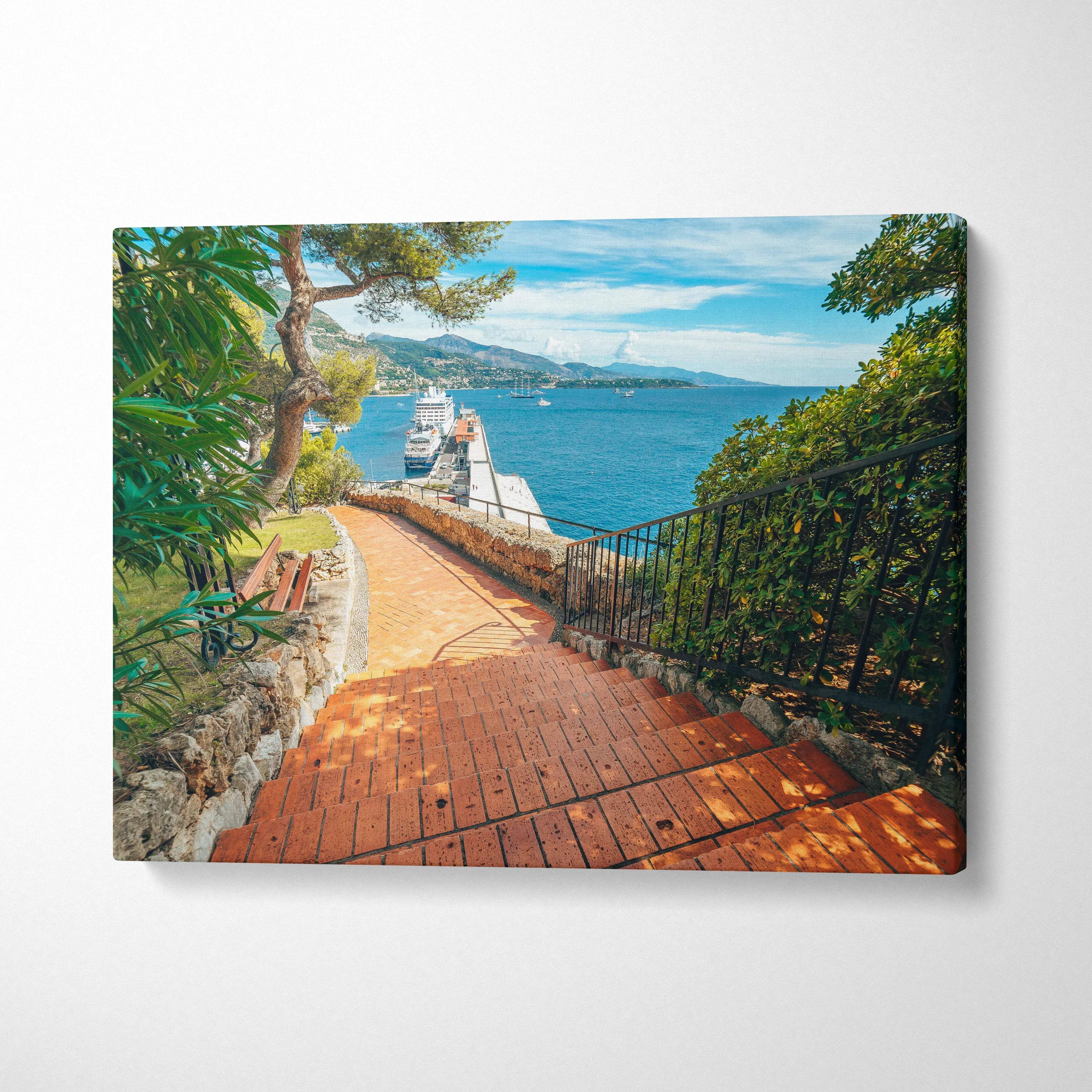 Canvas wall art featuring a sunlit brick pathway with lush greenery and ocean view under a blue sky.