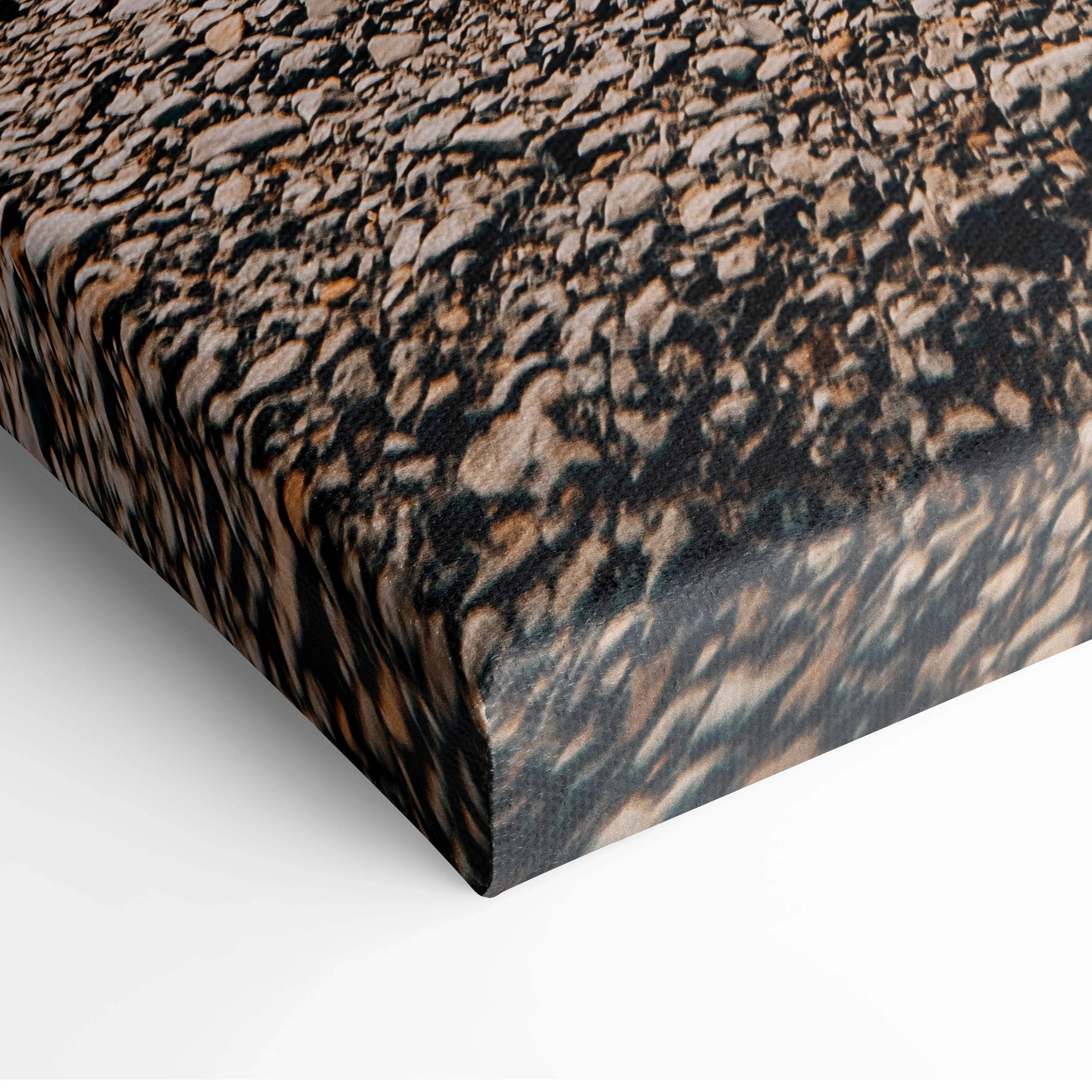 Canvas print of mixed brown and gray textured river rocks complementing serene icelandic waterfall landscape wall art