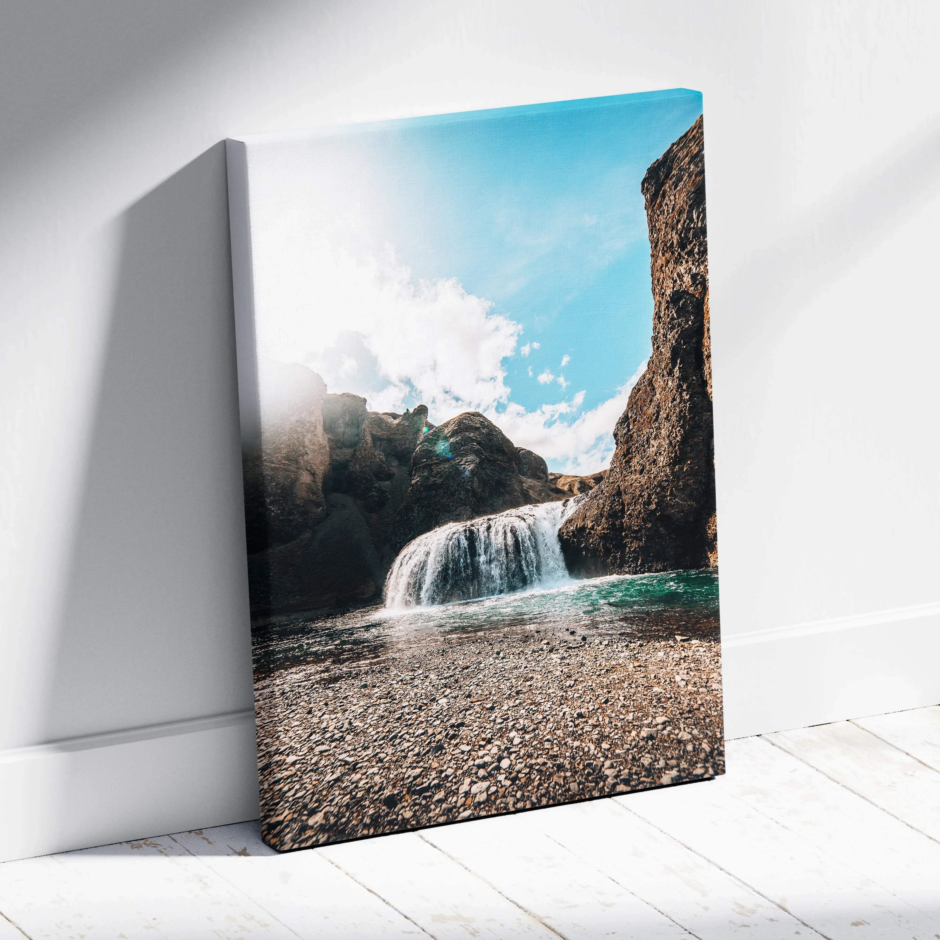 A framed canvas print of a vibrant Icelandic waterfall over sunlit rocks with turquoise water and bright blue sky