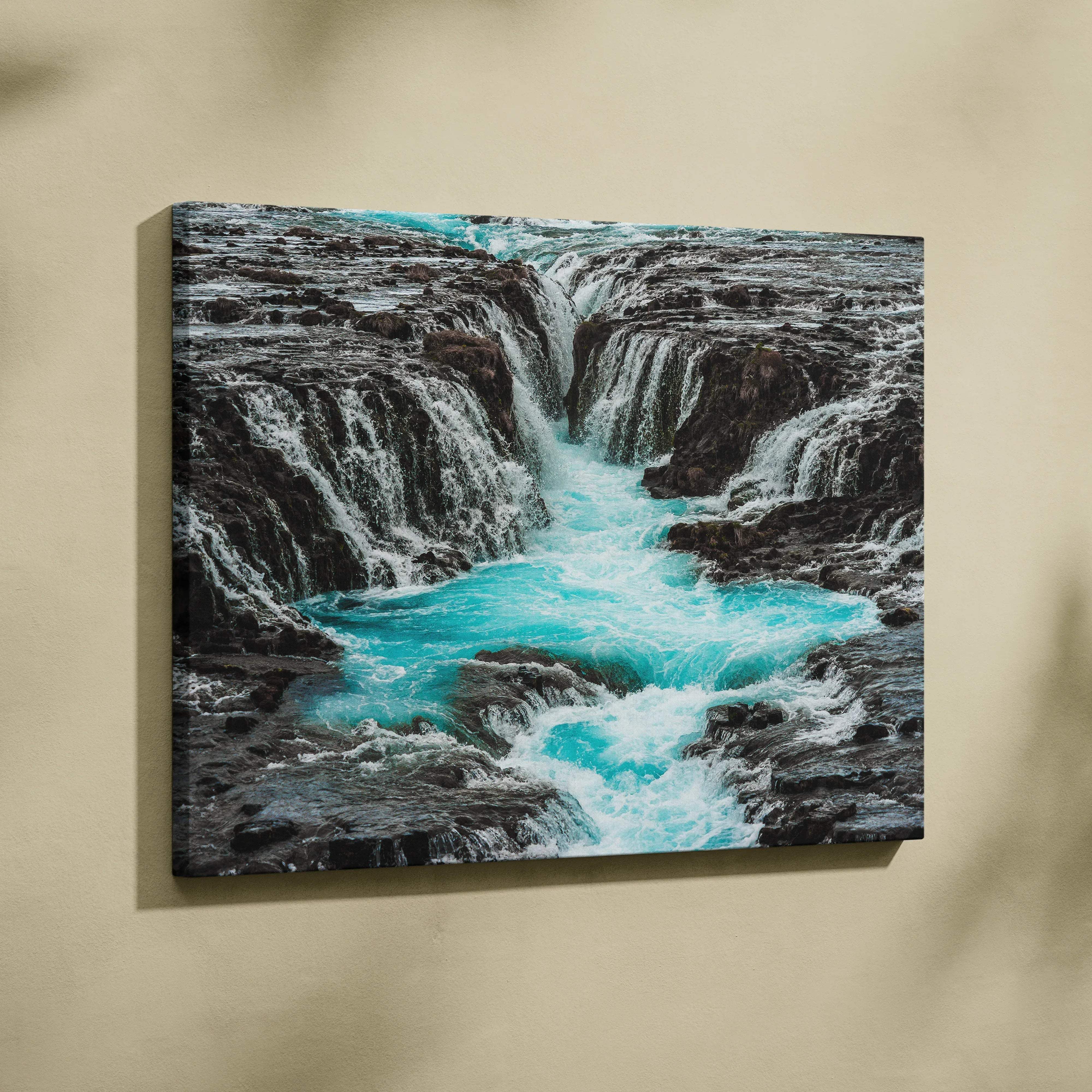 Canvas print of a vibrant turquoise waterfall cascading over dark rocks in an icelandic serene nature landscape