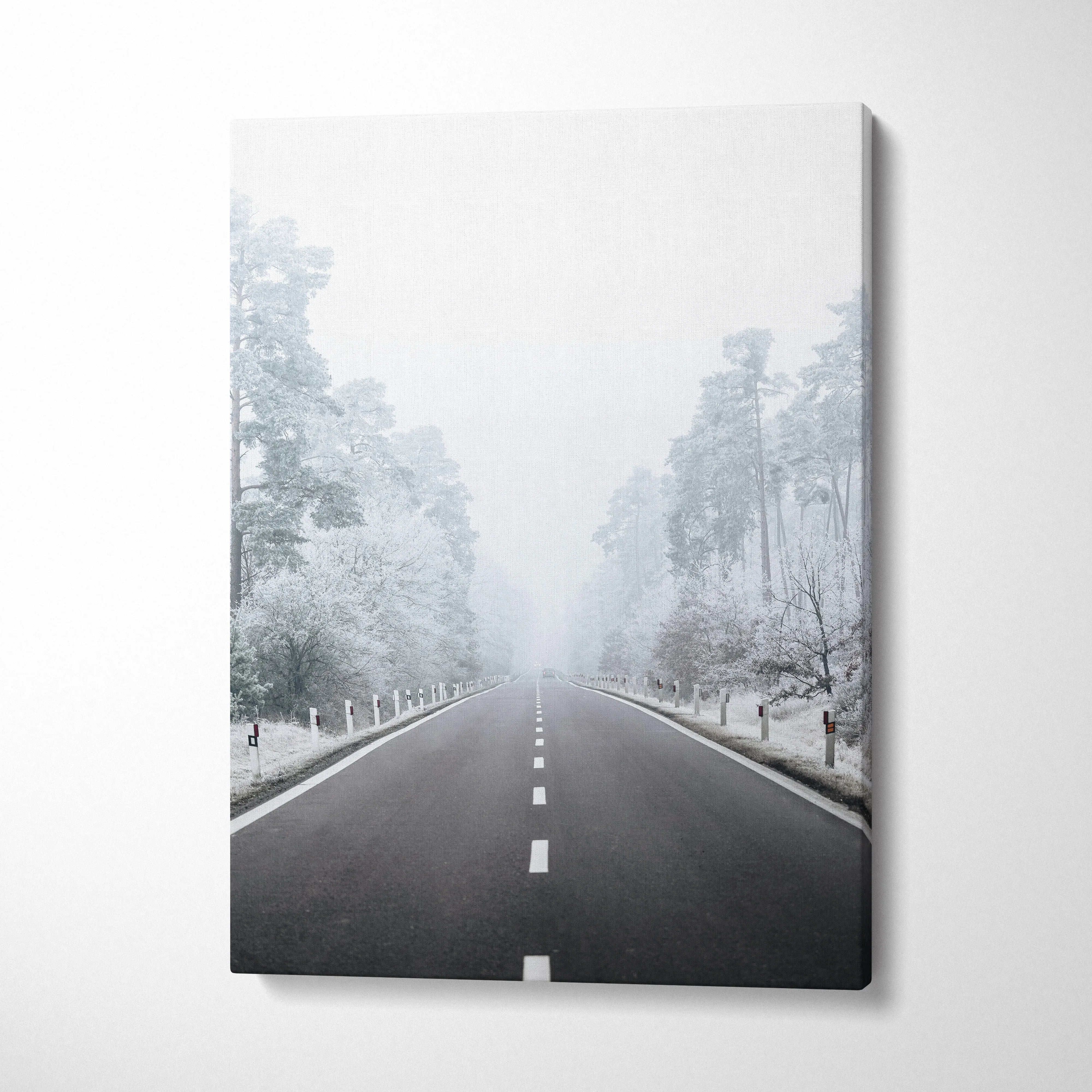 Vertical canvas wall art featuring a snowy road flanked by frosted trees in a serene winter landscape decor piece.