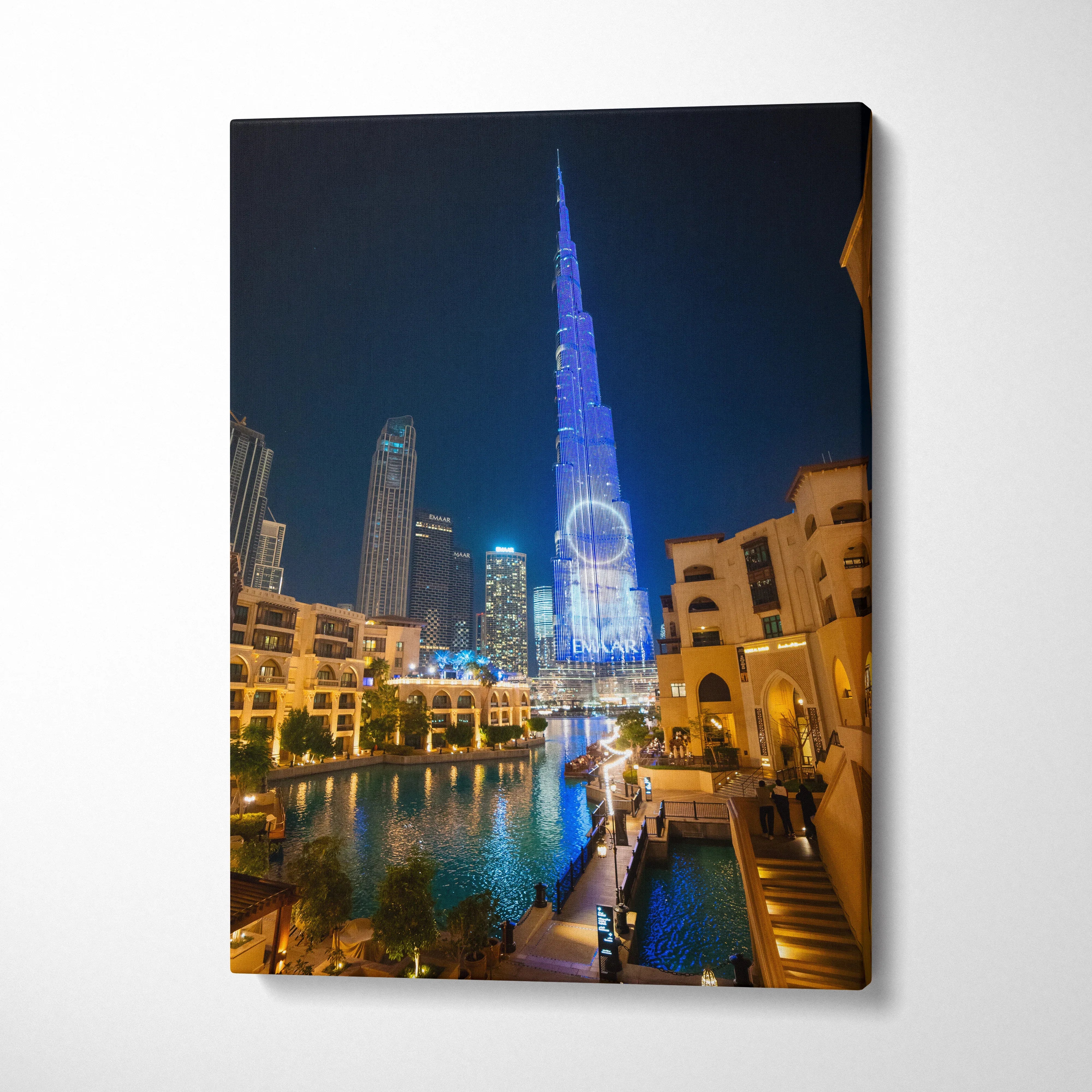 Canvas wall art of modern city skyline at night featuring illuminated skyscraper and water reflection.