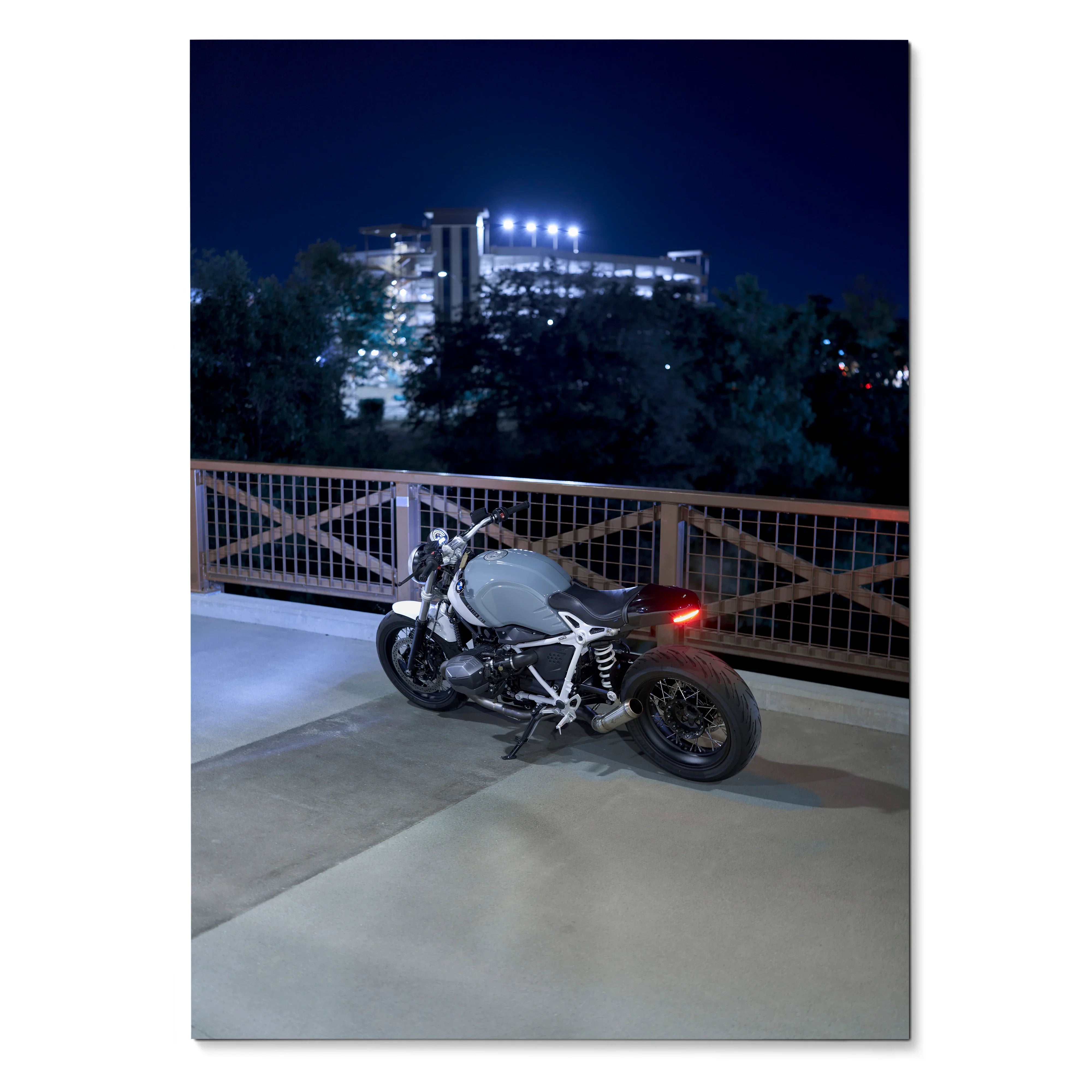 BMW R Nine T motorcycle parked on urban rooftop at night, poster wall art with city lights background.