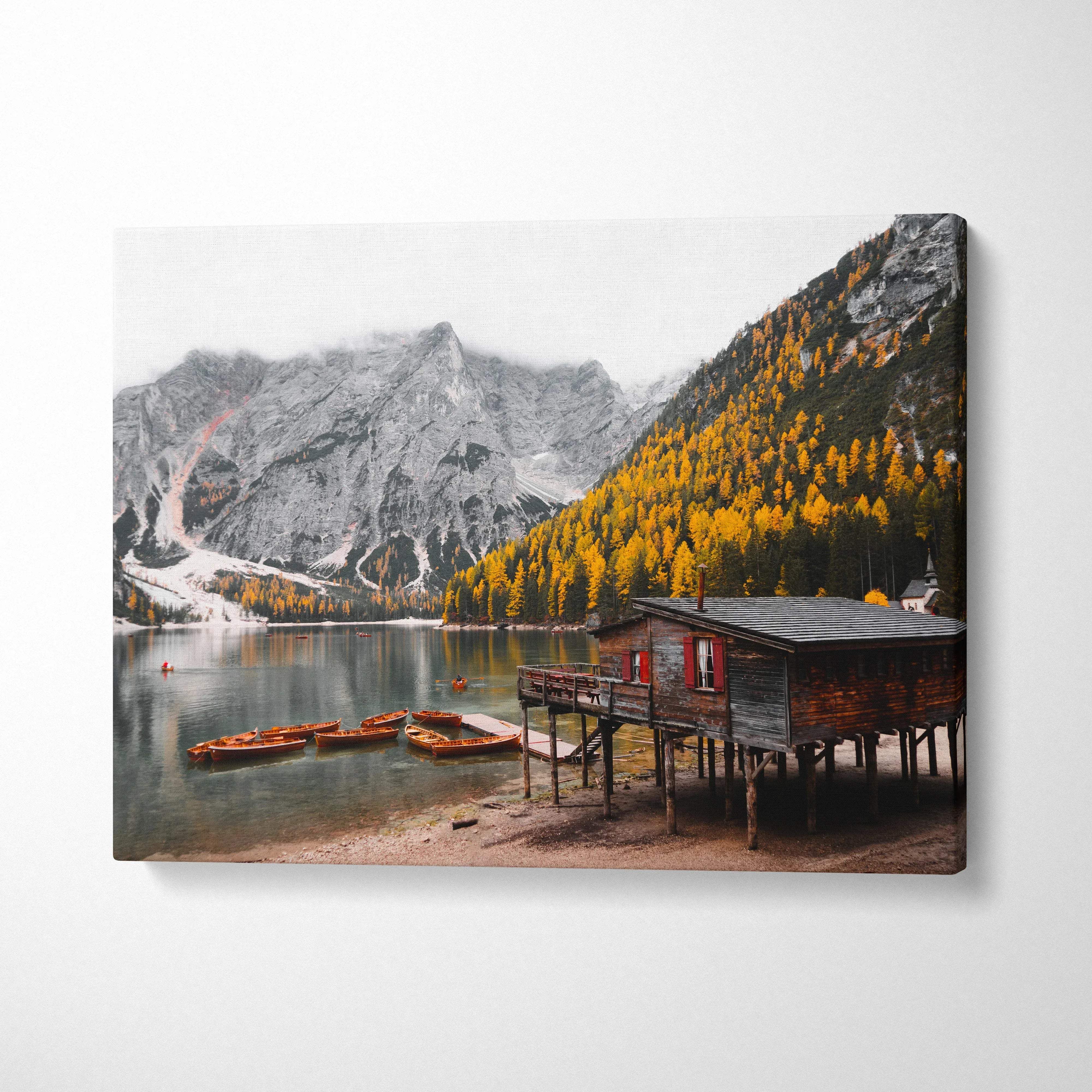 Canvas wall art featuring a serene autumn lake scene with golden foliage, mountains, and a rustic wooden cabin.