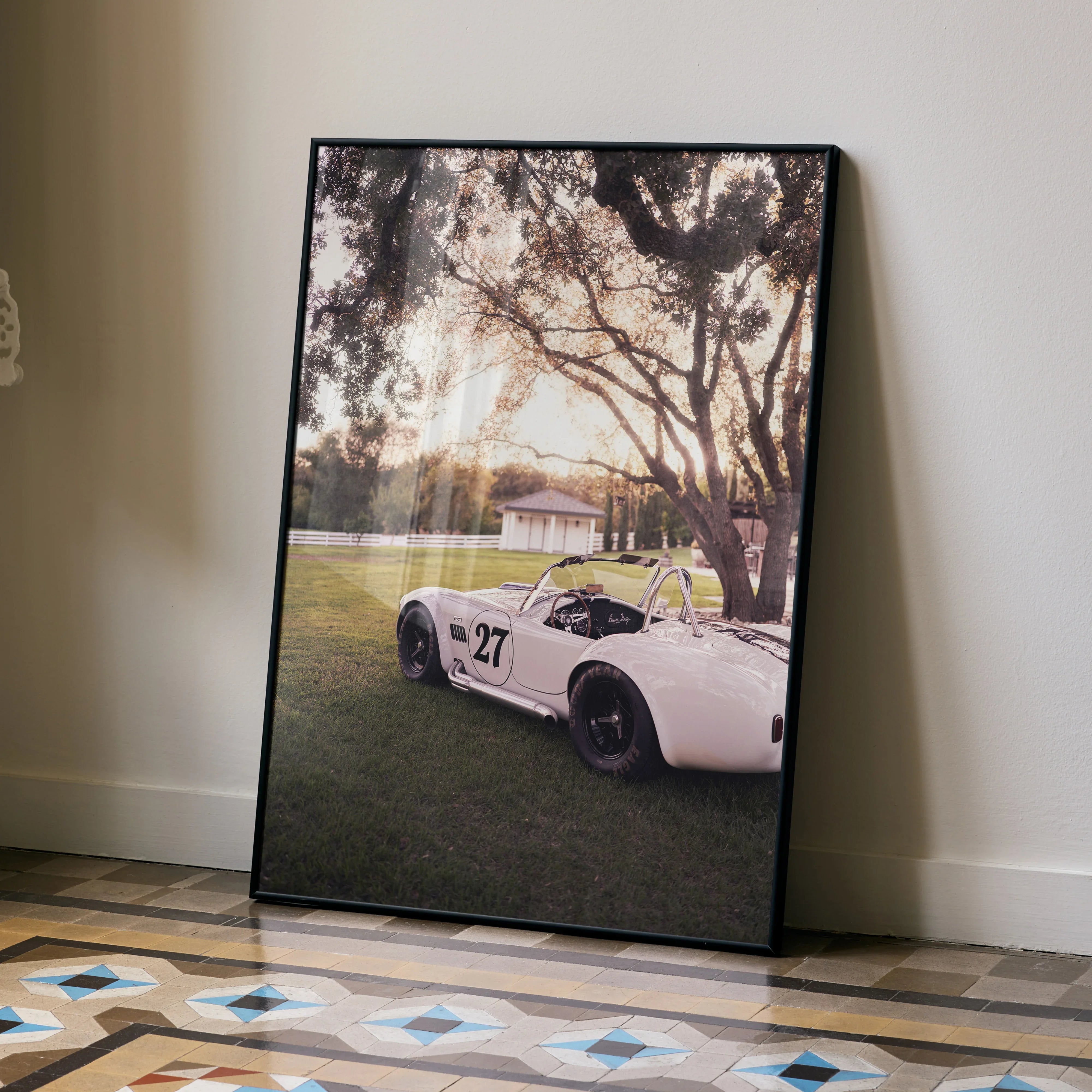 Shelby Cobra #002 poster showing vintage white race car under large trees at sunset, wall art with warm tones.