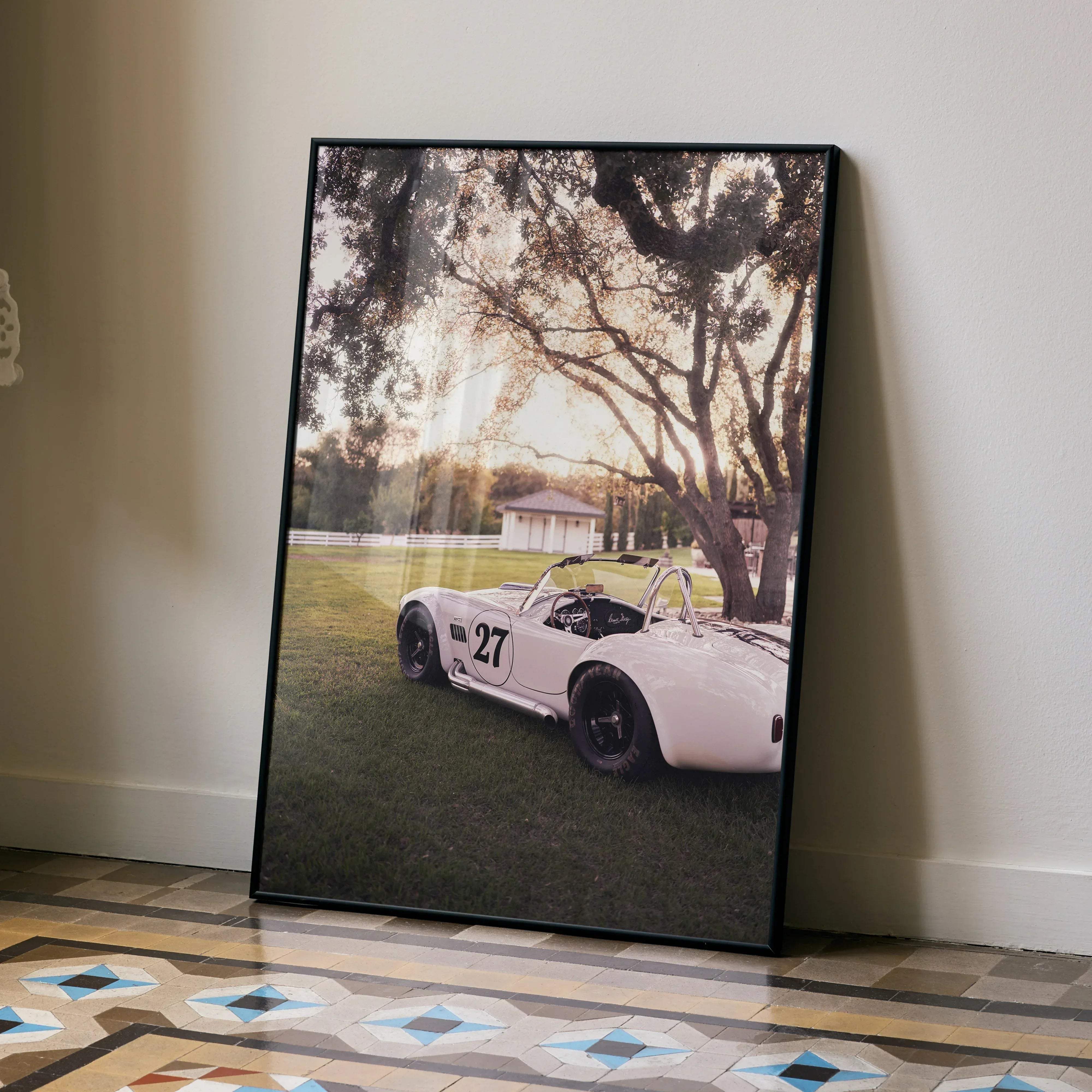 Black-framed limited edition shelby cobra #002 poster featuring vintage white race car number 27 parked on grass