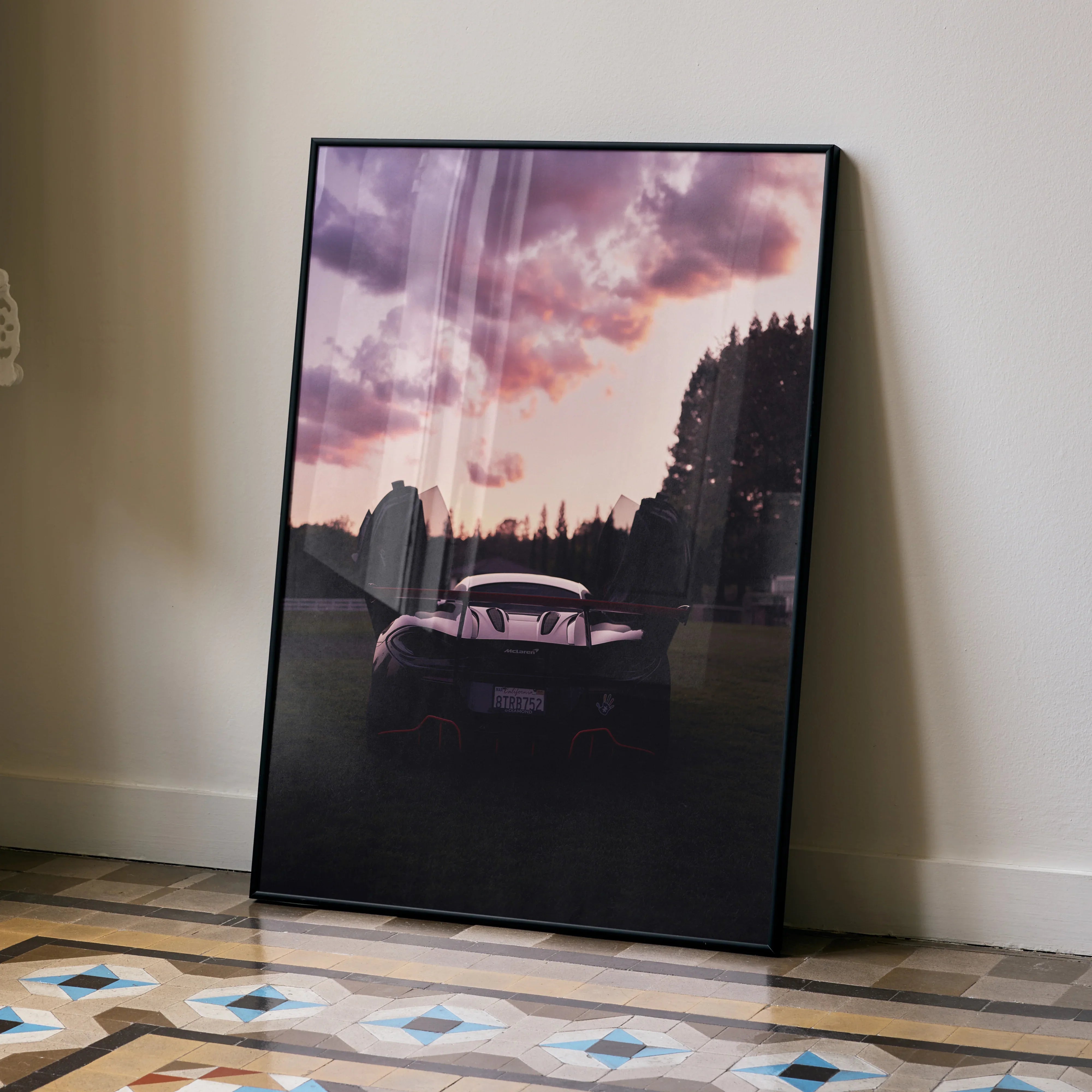 McLaren 570s luxury car poster with dramatic sunset sky, framed wall art leaning against wall.