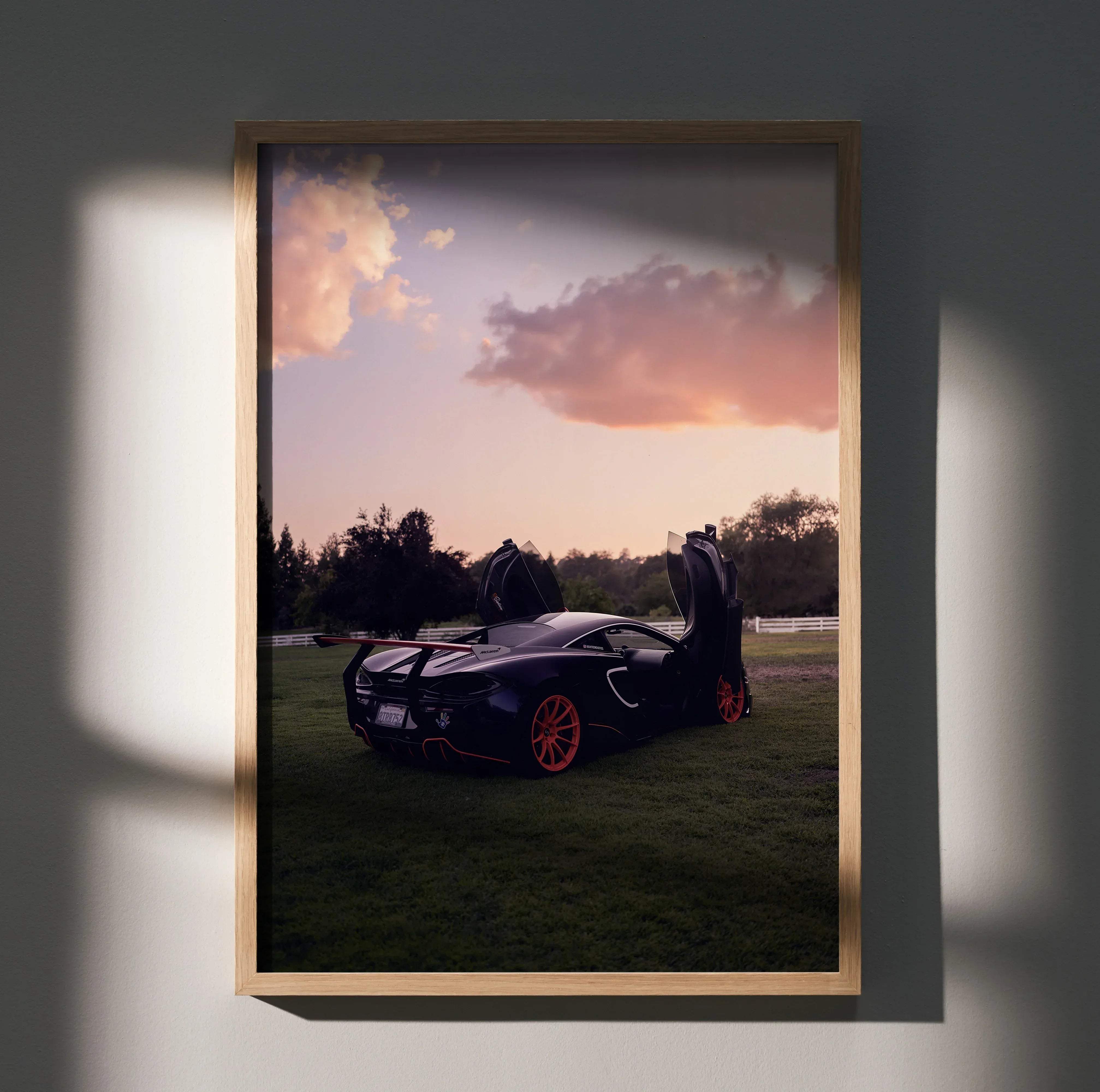 Black mclaren 570s sports car with vibrant red wheels and open doors framed in light wood automotive art poster