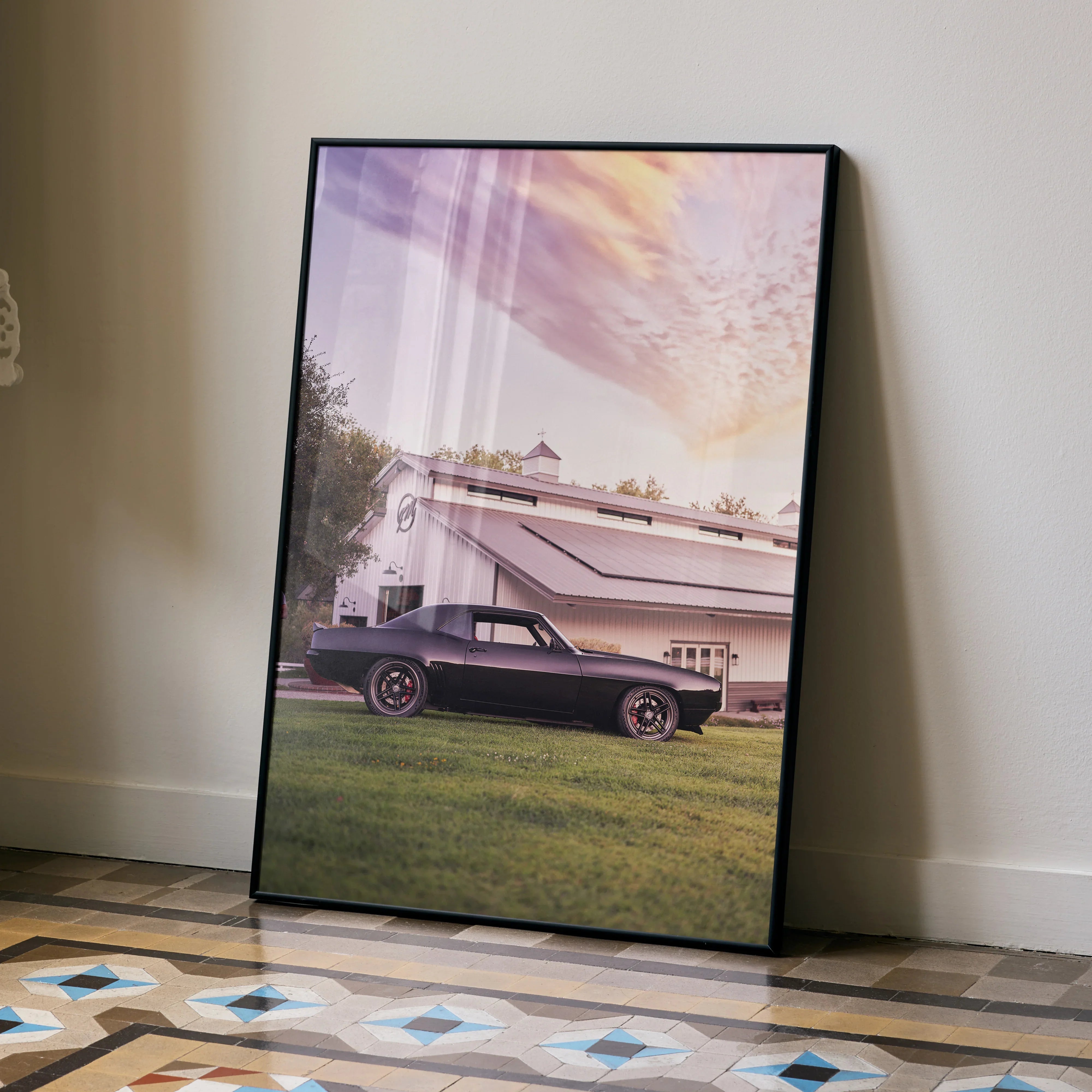 1969 Camaro parked on grass at sunset with vintage building background poster wall art.