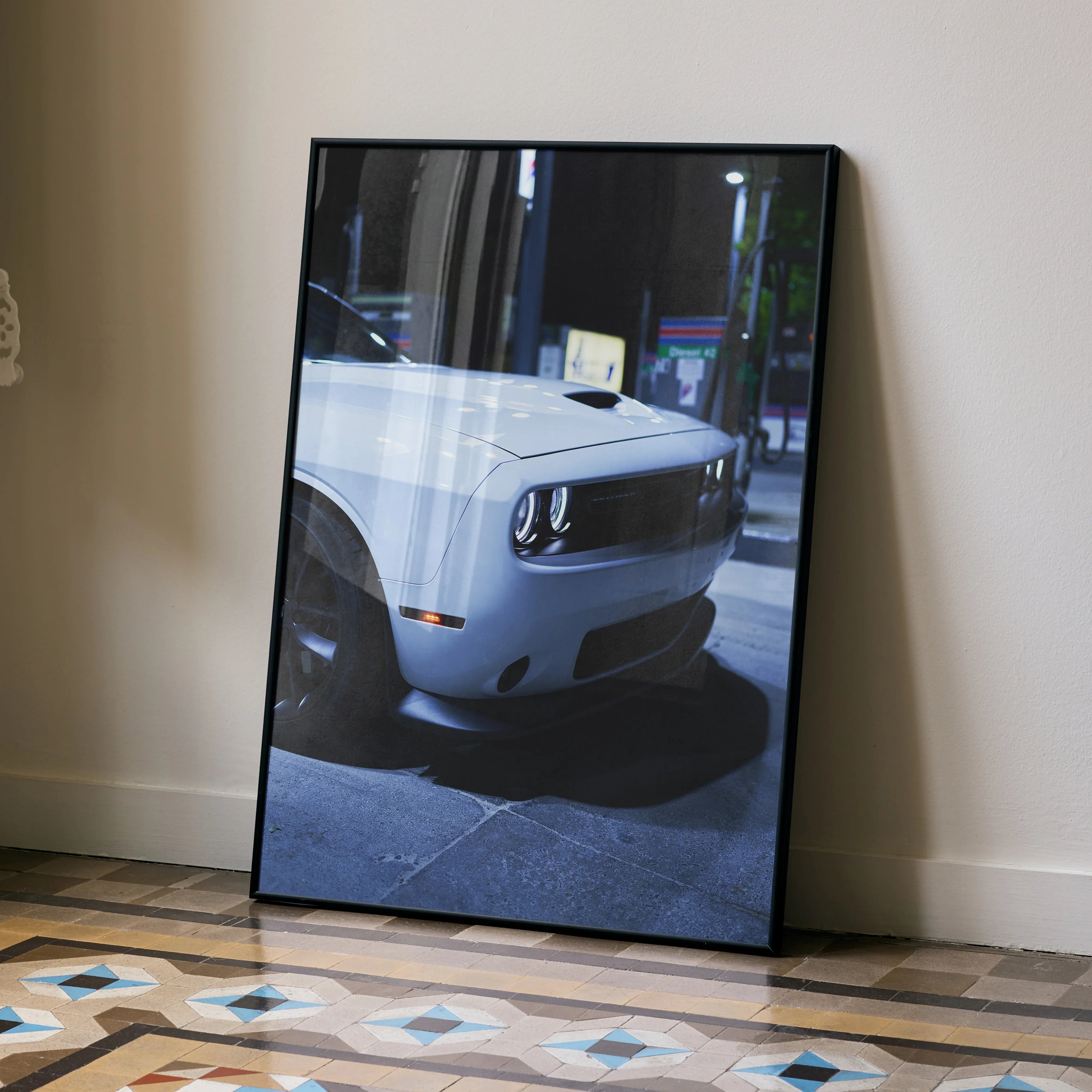 Dodge Challenger close-up poster wall art with black frame leaning on floor.