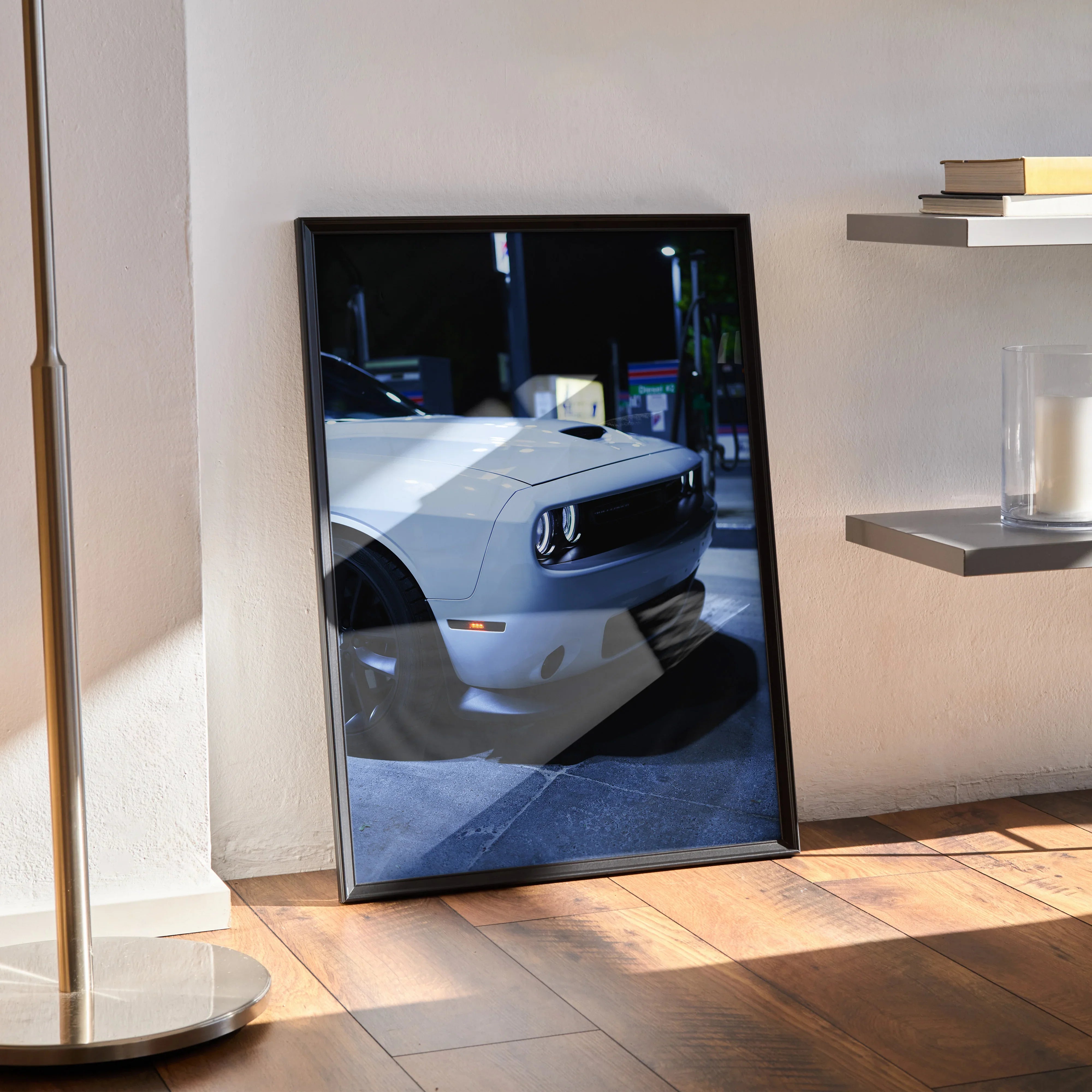 Dodge Challenger poster wall art featuring close-up front grille and headlights in black frame on wooden floor.