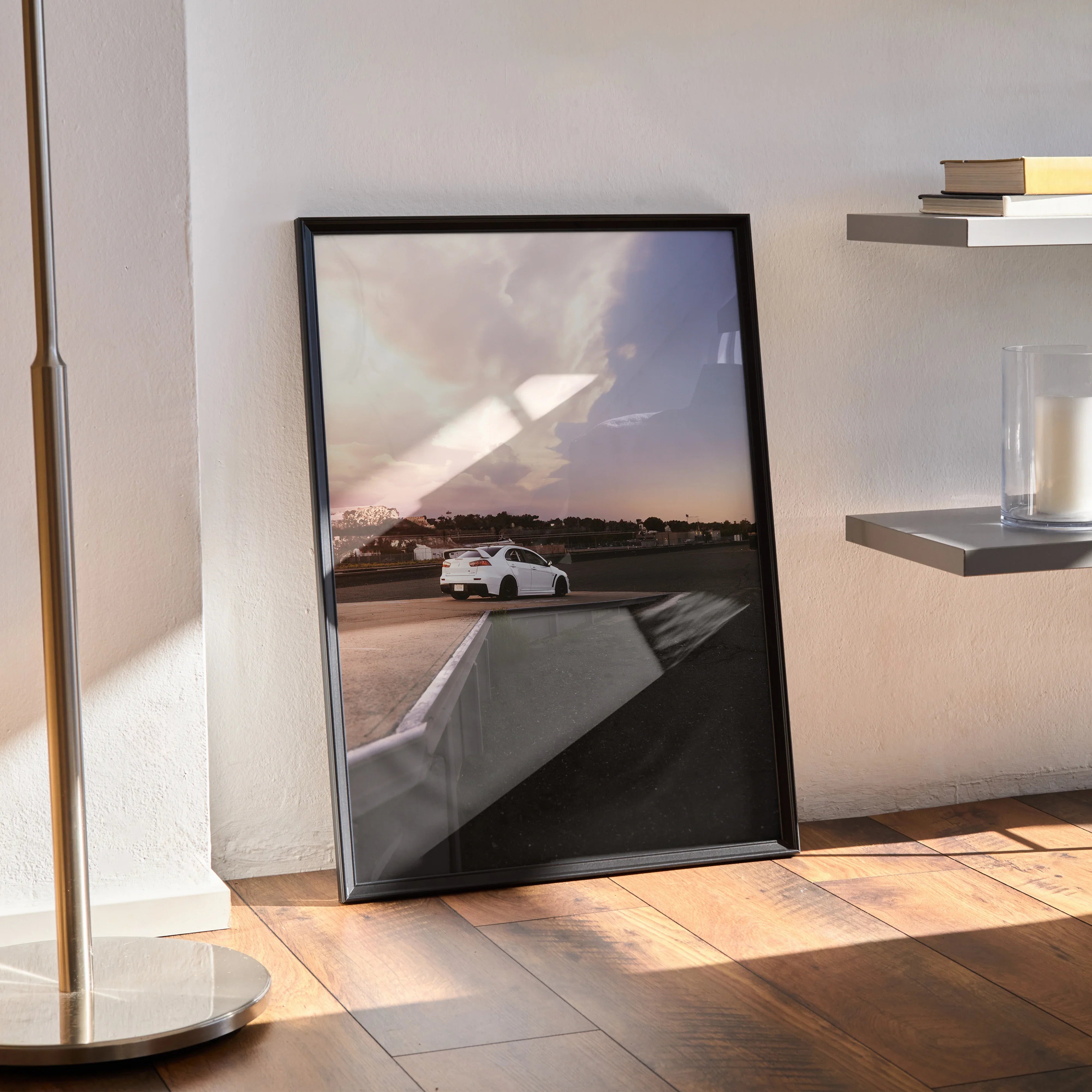 Mitsubishi Evo 10 poster leaning against wall with sunset sky and racetrack in background, black frame wall art.