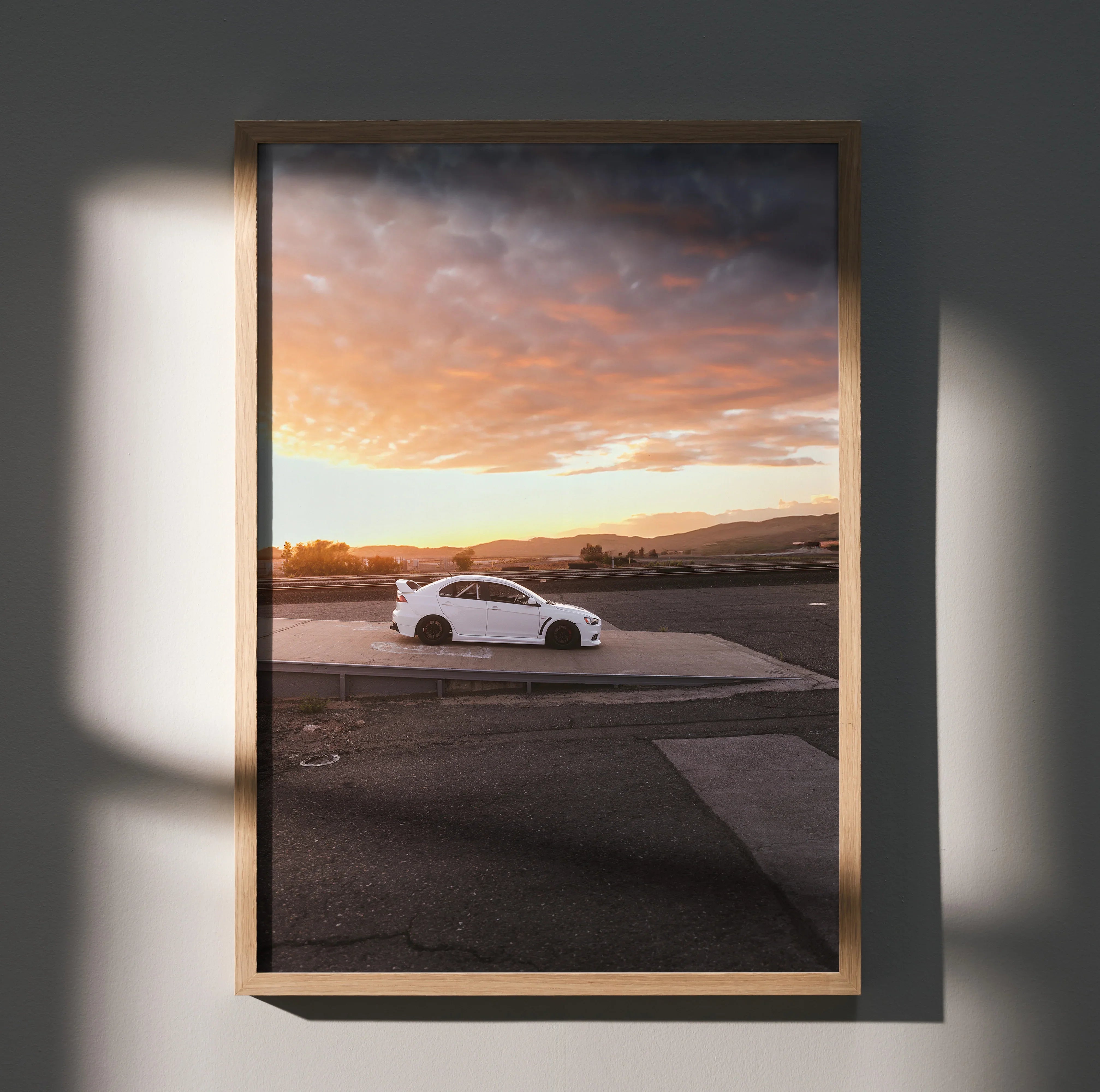 Mitsubishi Evo 10 poster wall art showing white car on open road under orange sunset sky.