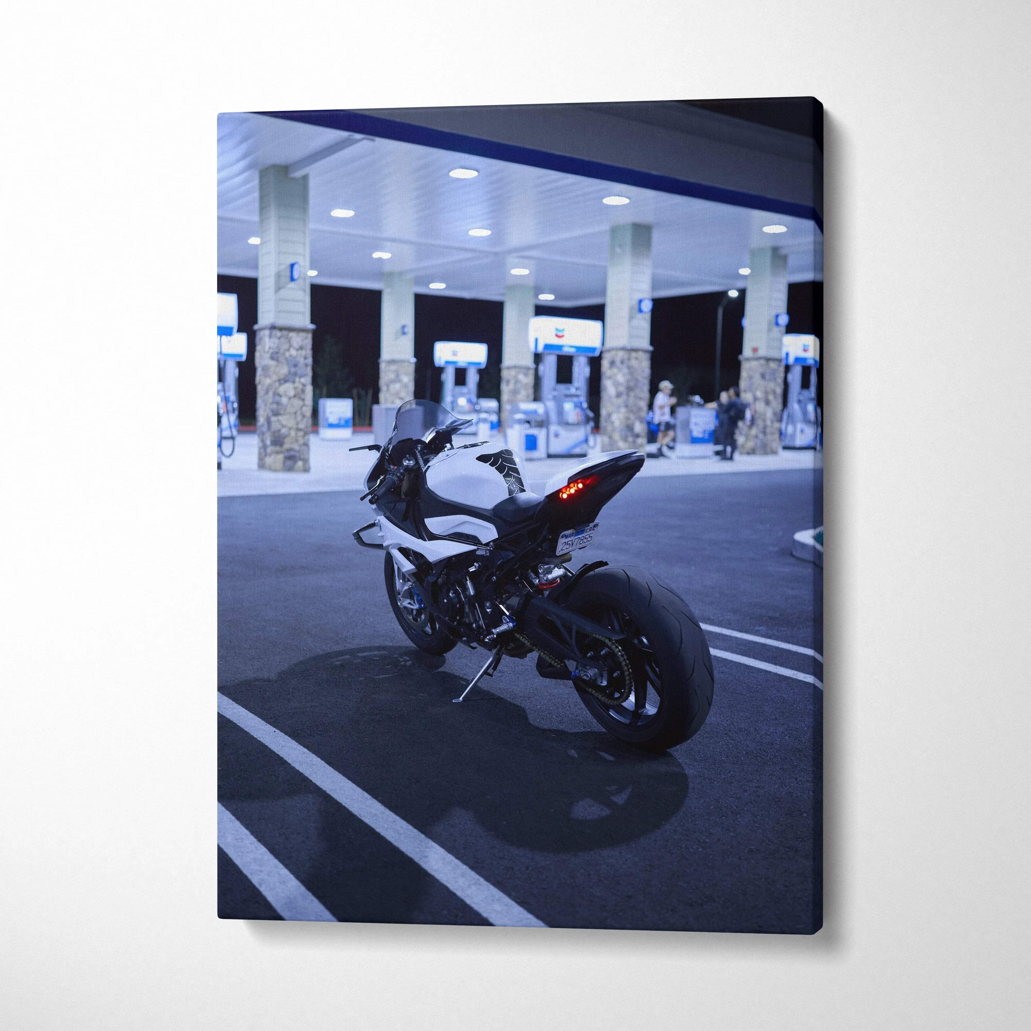 Vertical canvas wall art featuring a black BMW S1000RR motorcycle parked at a gas station at night.