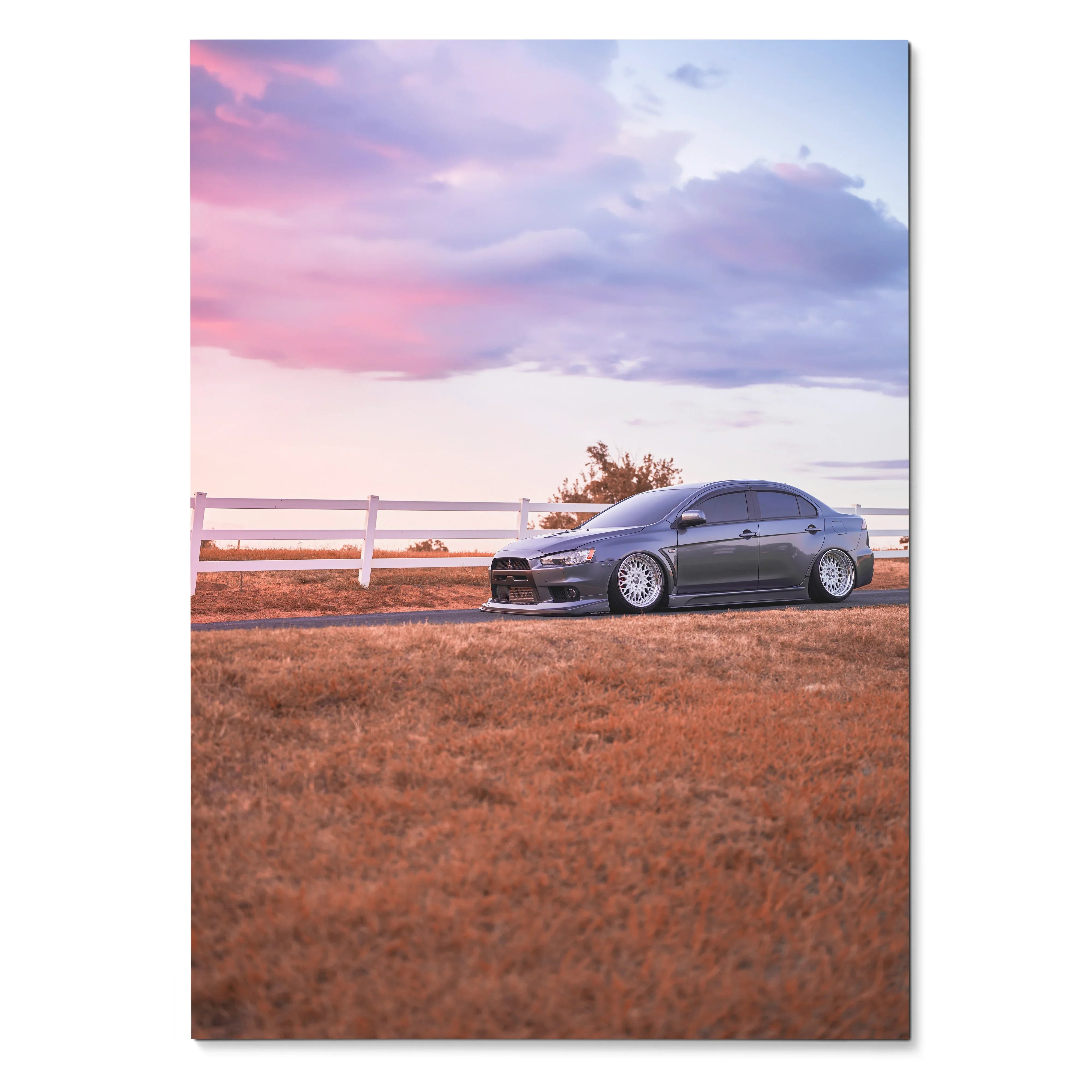 Mitsubishi Evo 10 parked on grassy field under pastel sunset sky poster wall art.