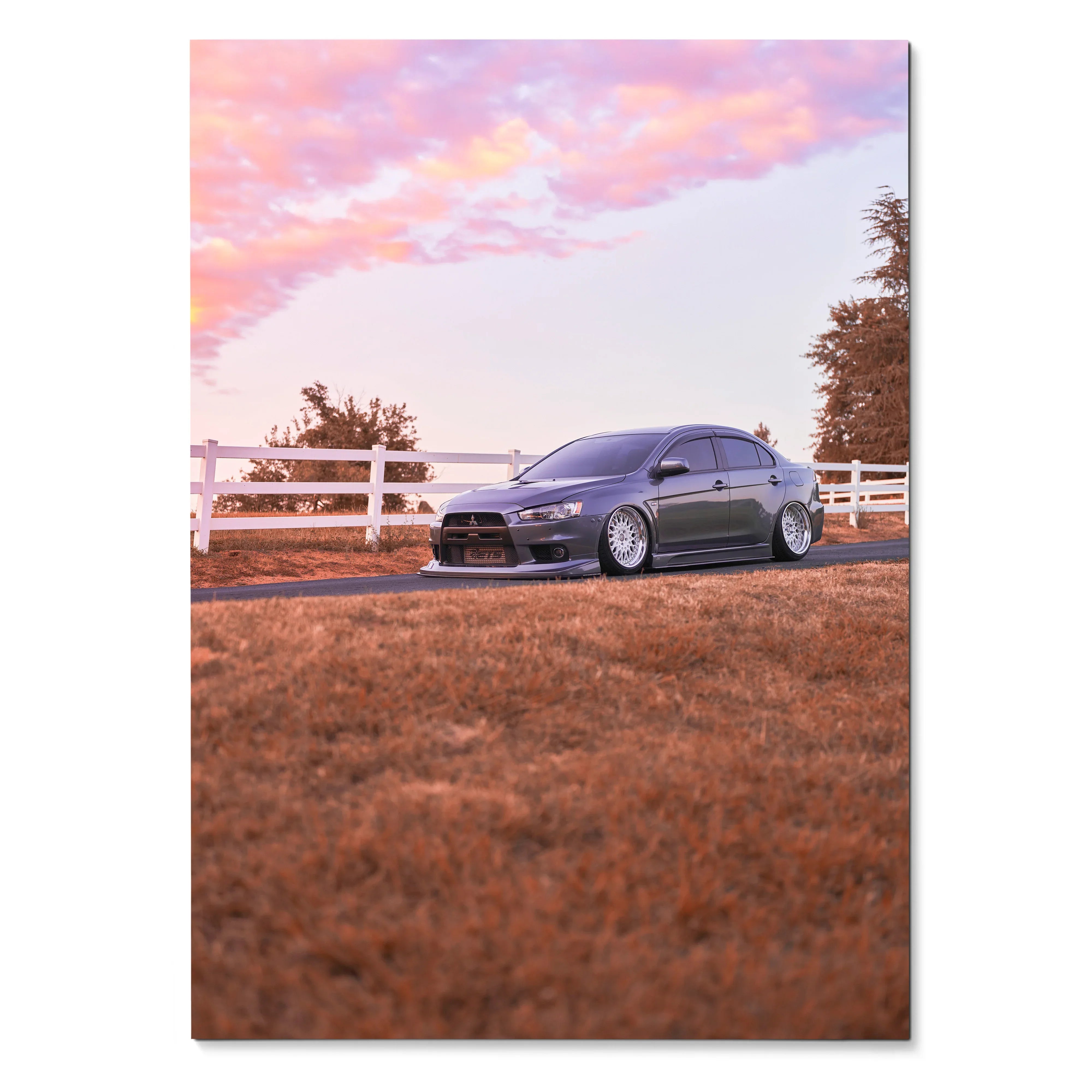 Mitsubishi Evo 10 parked on grass at sunset with pink sky, poster wall art.