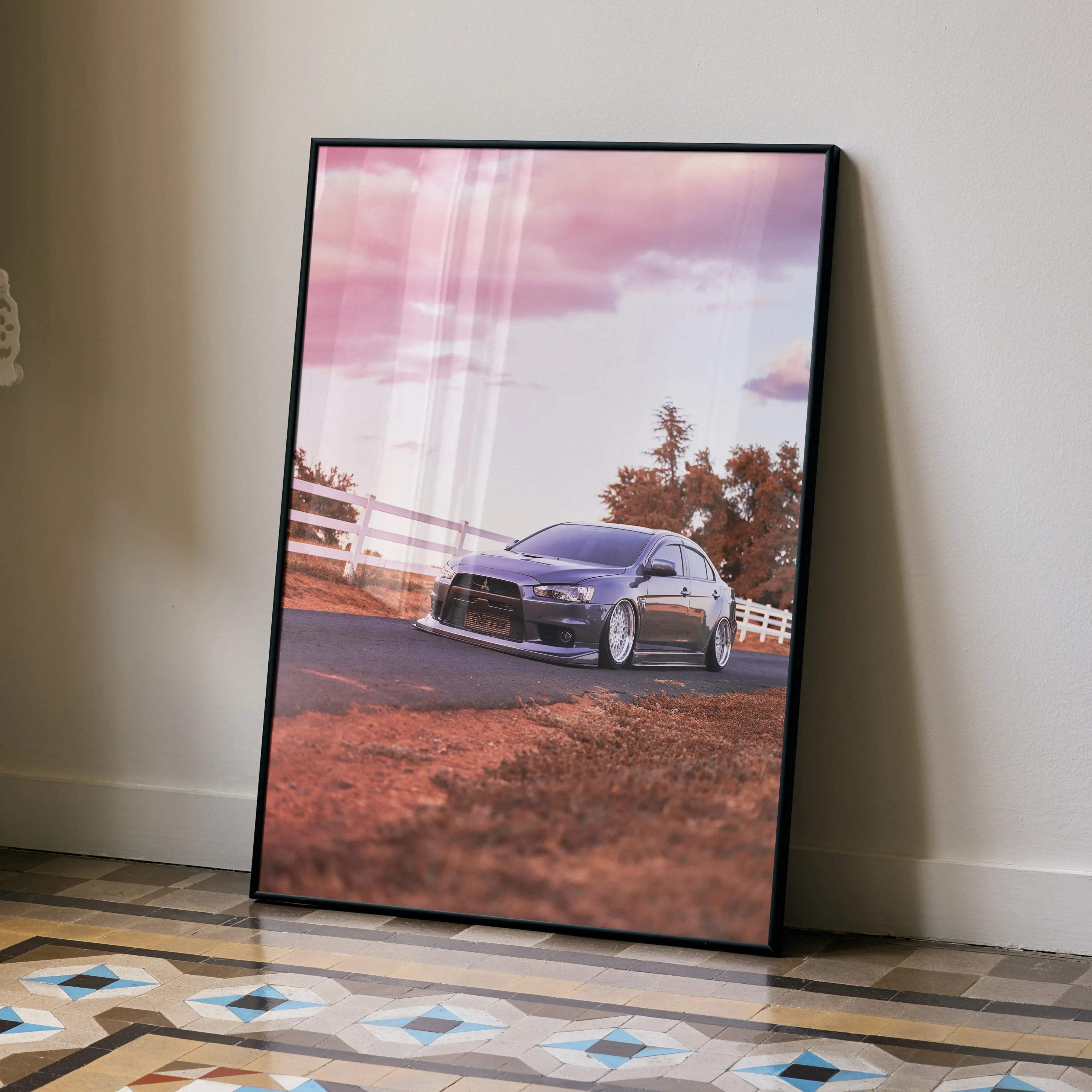 Black-framed poster of a dark blue mitsubishi lancer evolution sports car under pink and white skies for wall decor