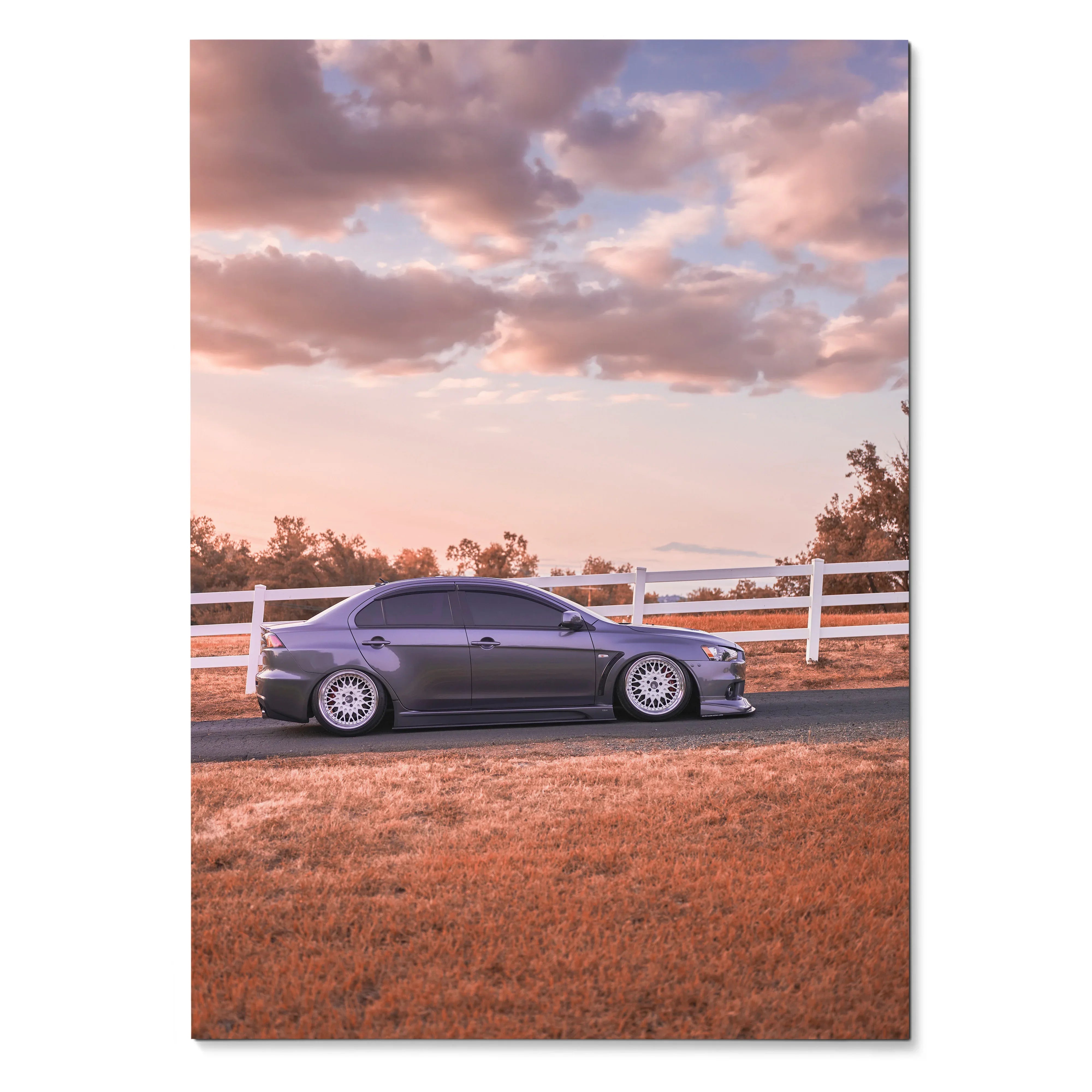 Mitsubishi Evo 10 poster showing sleek gray car parked by white fence under colorful sunset sky wall art.