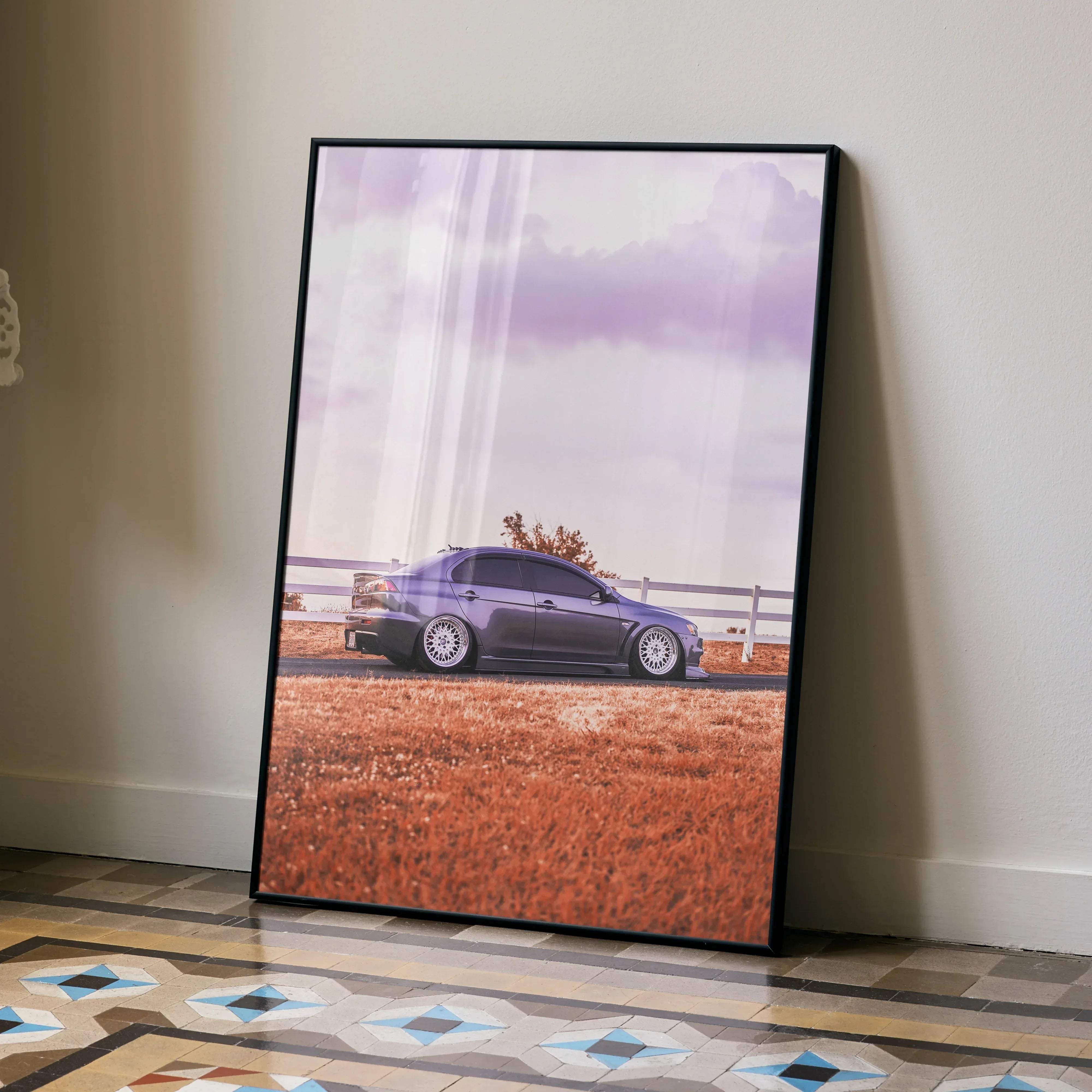 Black-framed poster of a purple mitsubishi evo 10 sedan parked beside a white fence under a cloudy sky
