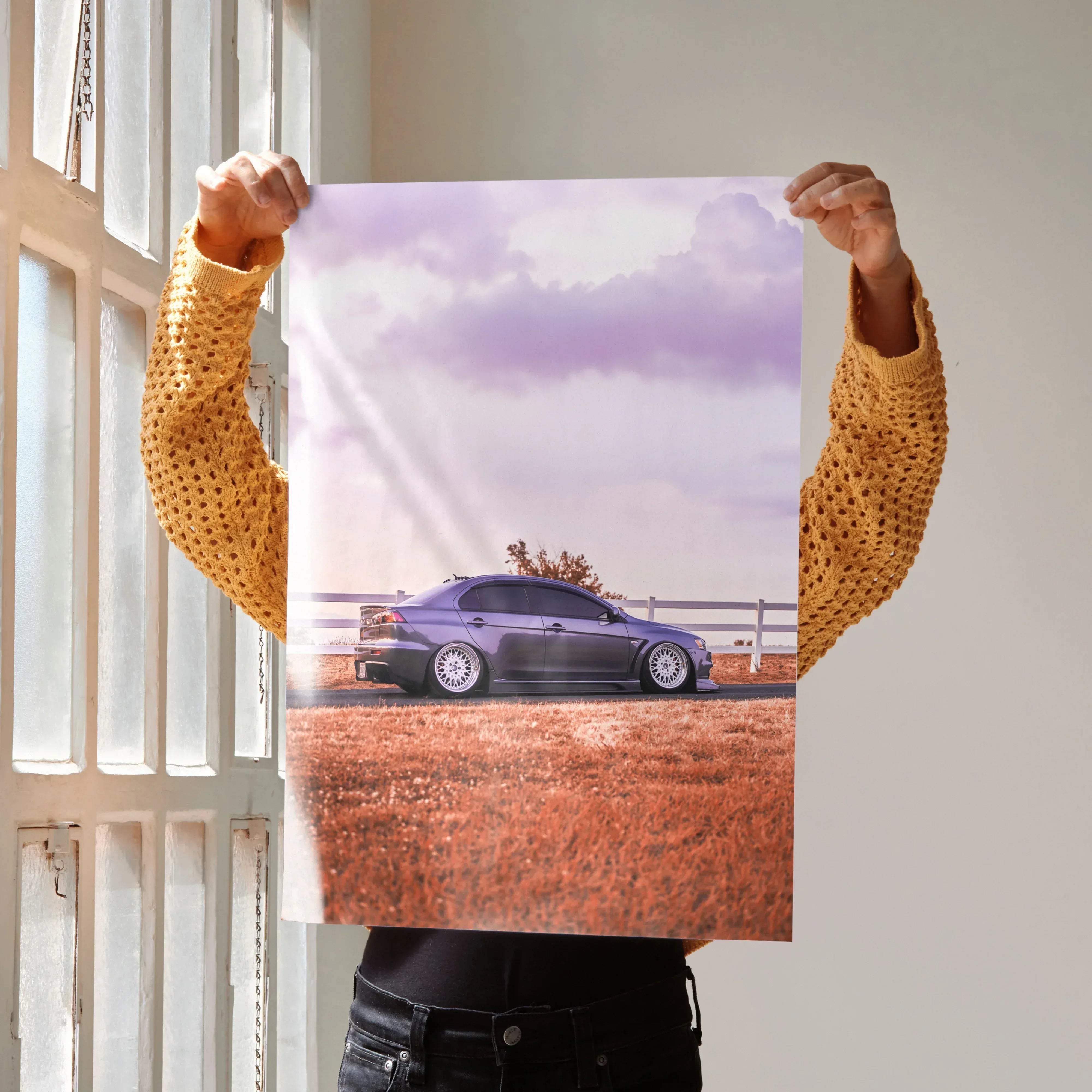 A matte-finish poster of a sleek dark purple mitsubishi evo 10 parked in a field under a lavender sky